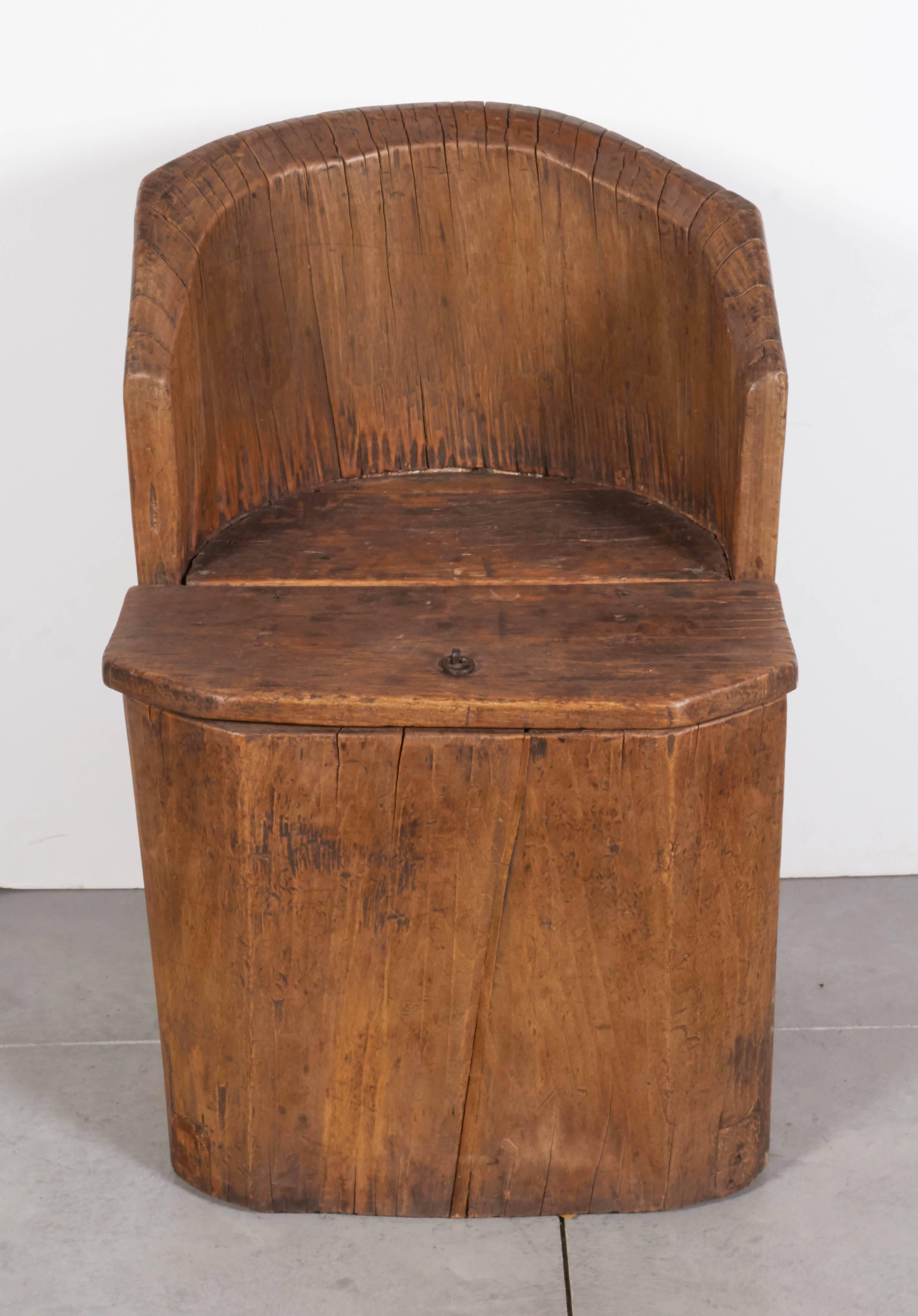 An unusual antique Chinese money chair carved out of a single piece of poplar wood. This heavy chair was used for the storage of money protected by the person sitting on it. Other than the lift off seat to give access to the hollow interior, this