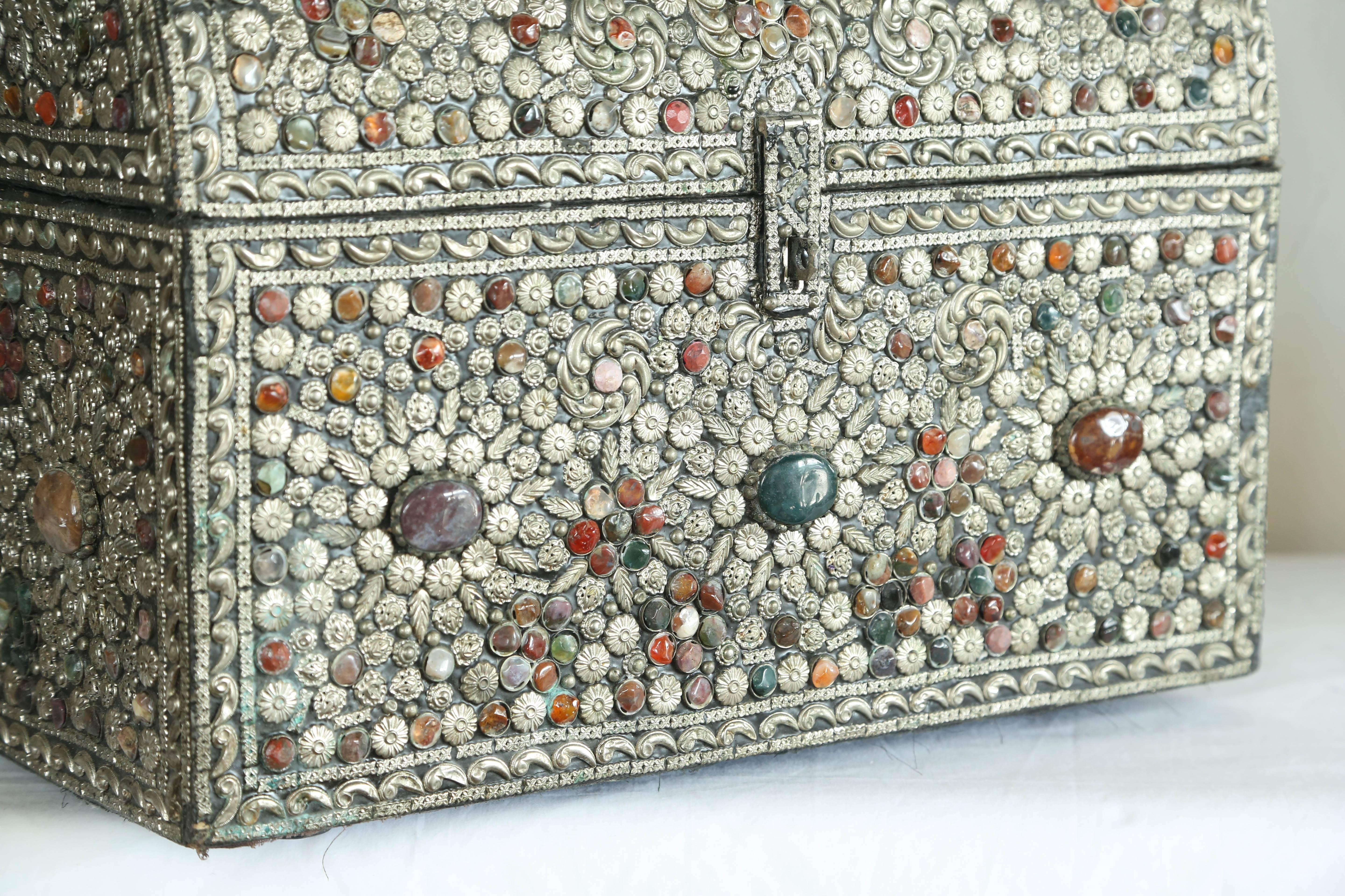 Large trunk covered in silver metal and assorted colored stones.