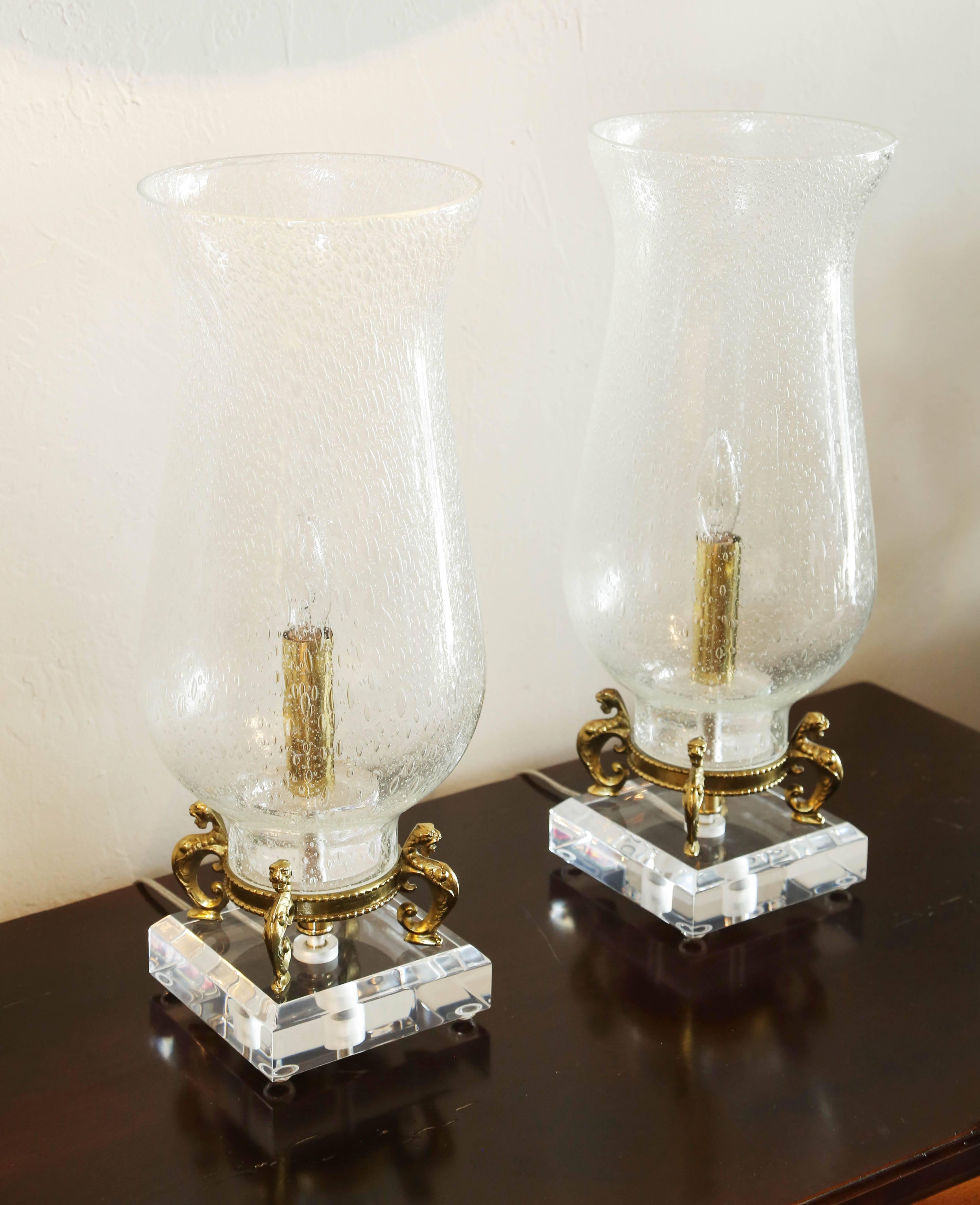 Pair of Lucite base with brass sea lions supporting seeded glass hurricane lights.