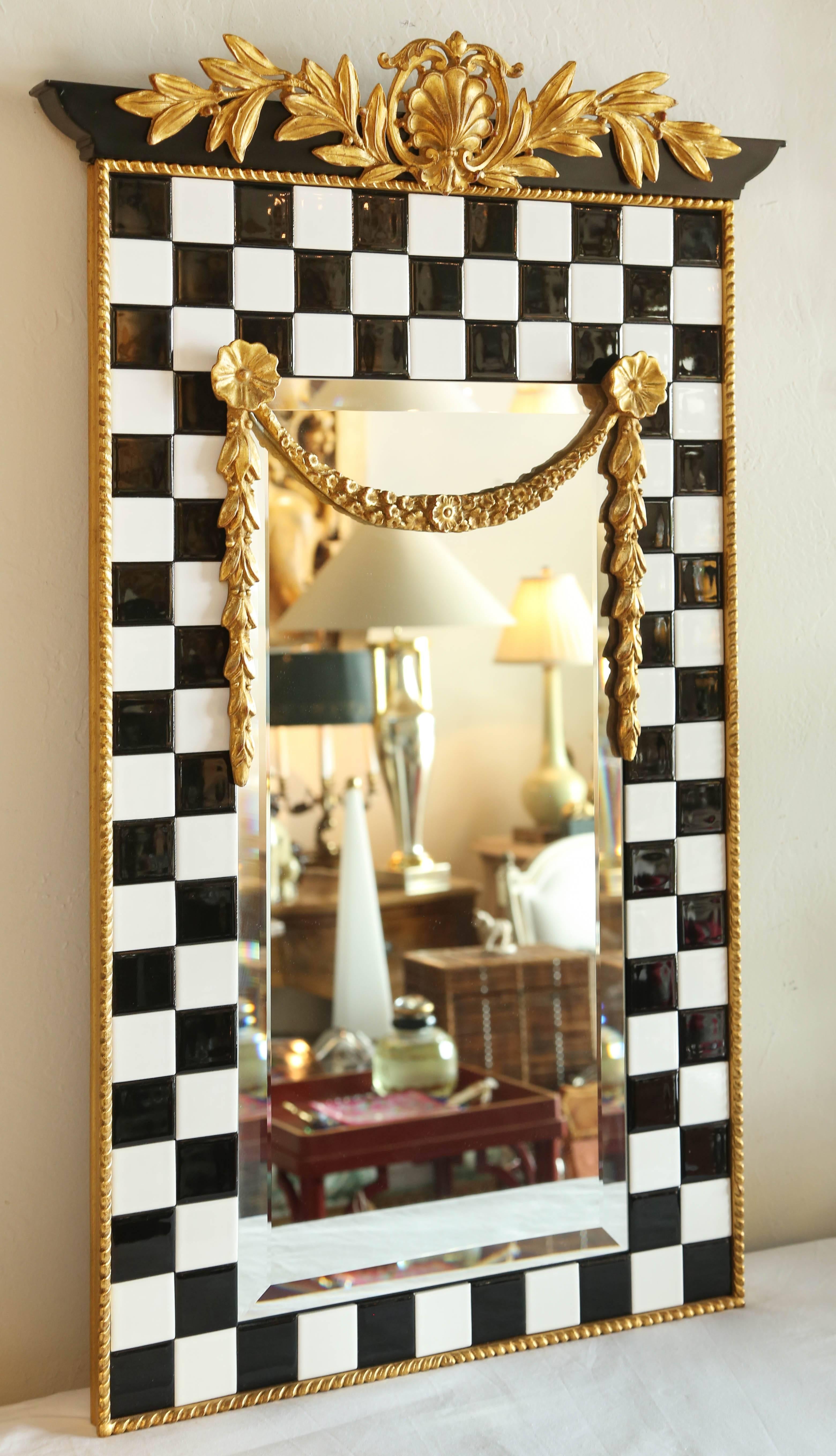 Black and white tiled mirror frame with carved and gilded accents at top and middle.