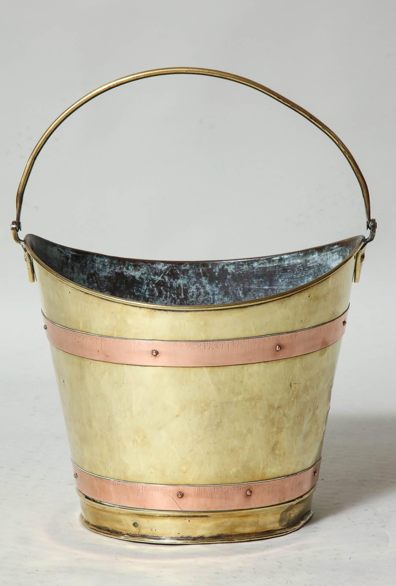 Unusual 19th century boat shaped bucket in brass with copper banding and brass carrying handle, useful for a waste-paper basket or for kindling next to a fireplace.