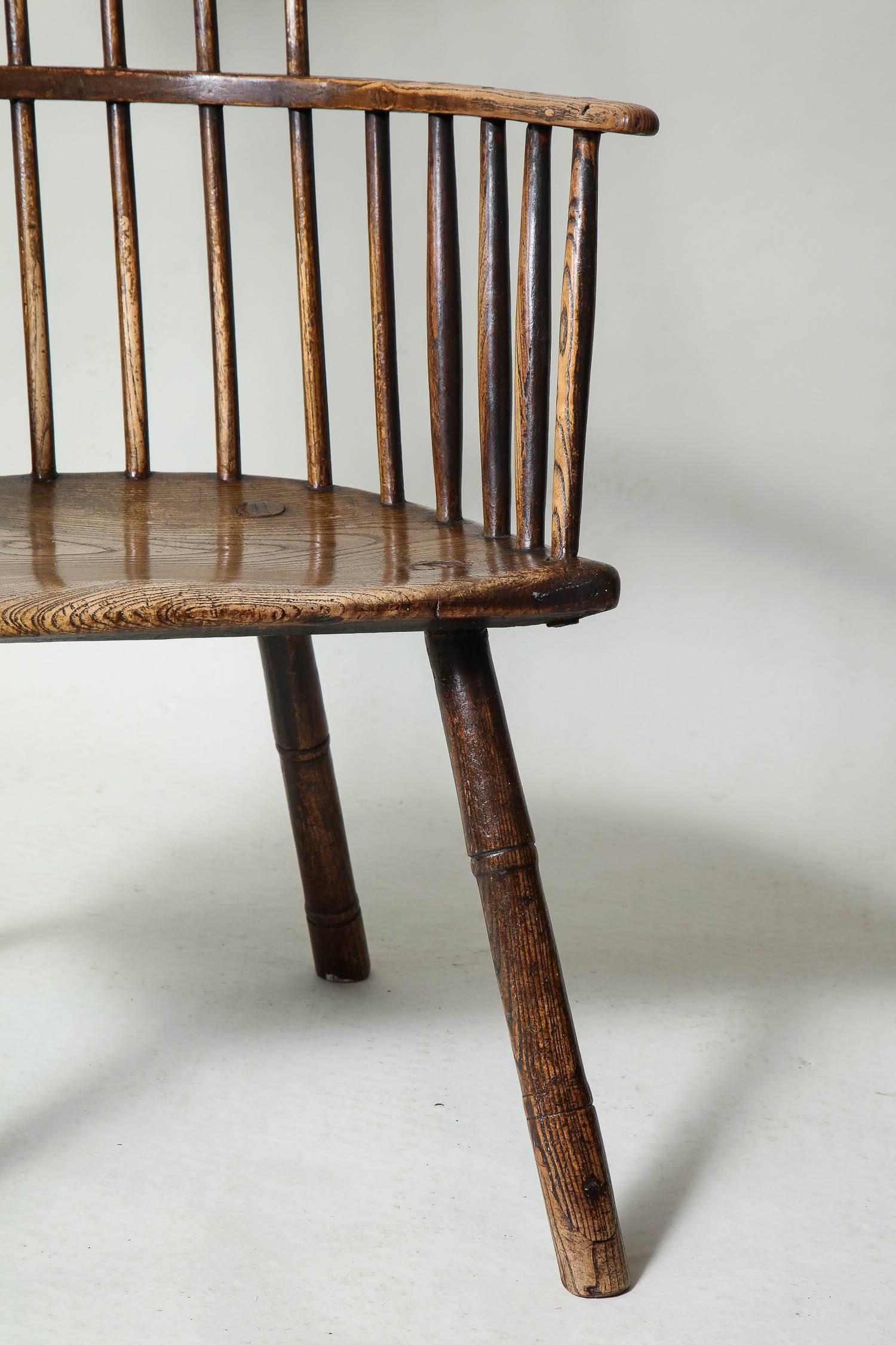 Fine English 18th century rustic windsor armchair having simple shaped comb over seven spindle back, the continuous bentwood arm with a further ten spindle supports on shaped and saddled ashwood seat, standing on ring turned spayed legs and