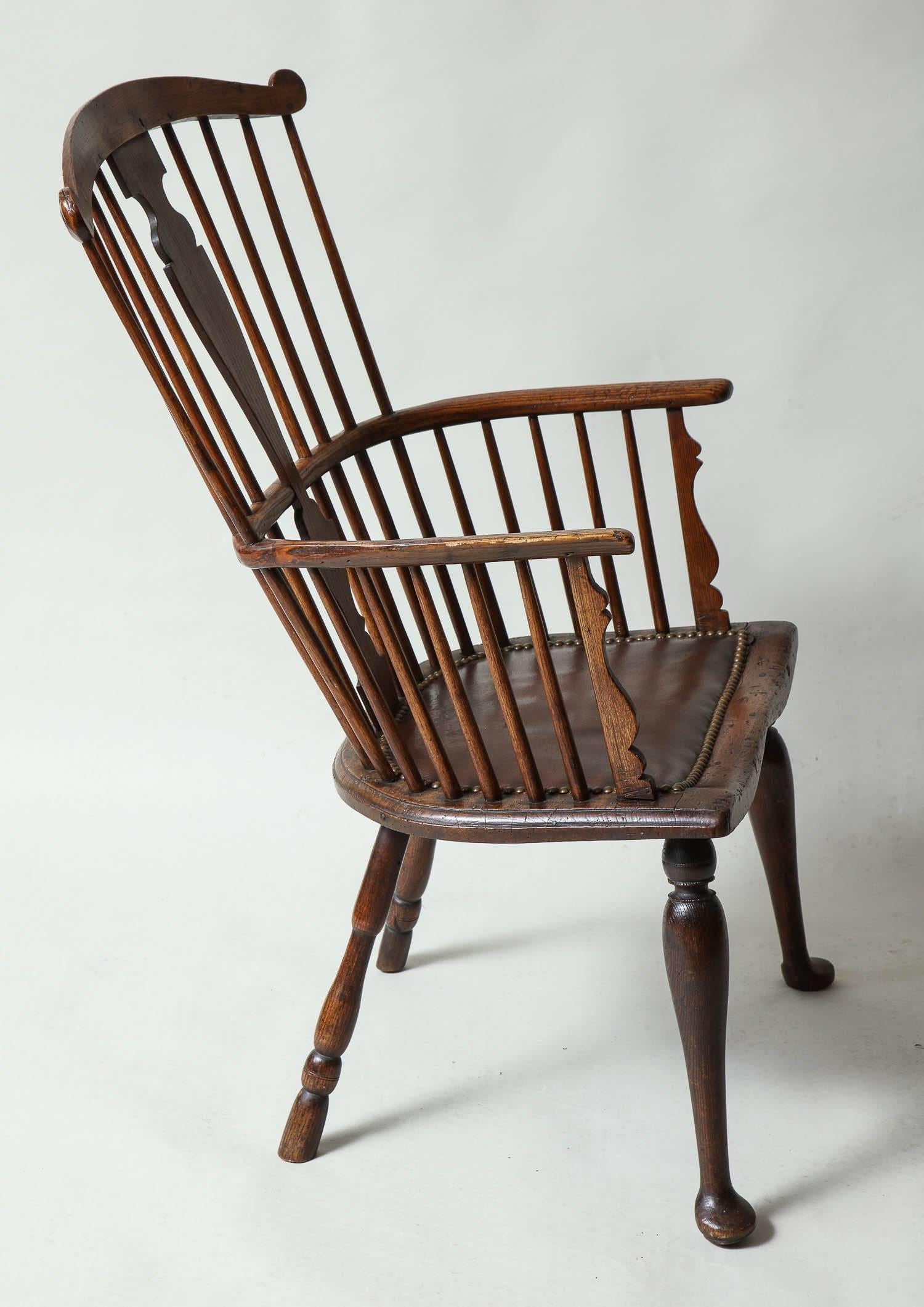 Very good 18th century English Windsor armchair, the shaped crest with lollipop ends over solid vasiform back splat and spindles, the arms with scalloped supports, the saddled seat with beaded edge and leather padded seat, standing on turned legs,