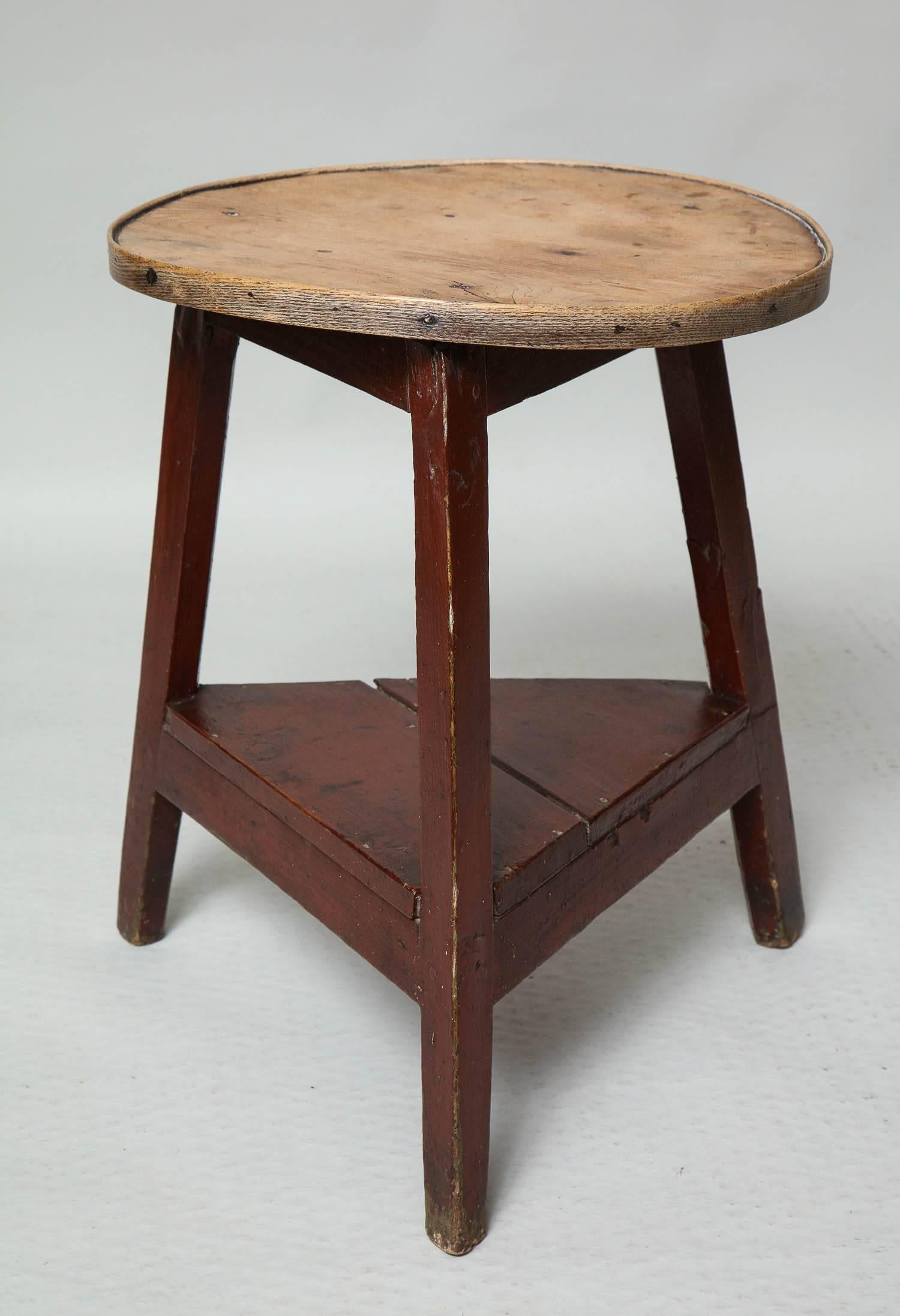 Good early 19th century scrubbed elm cricket table, the single board top with 'elm twist' surface and with banded edge, over three splayed legs joined by under tier stretcher base all retaining original deep red paint.