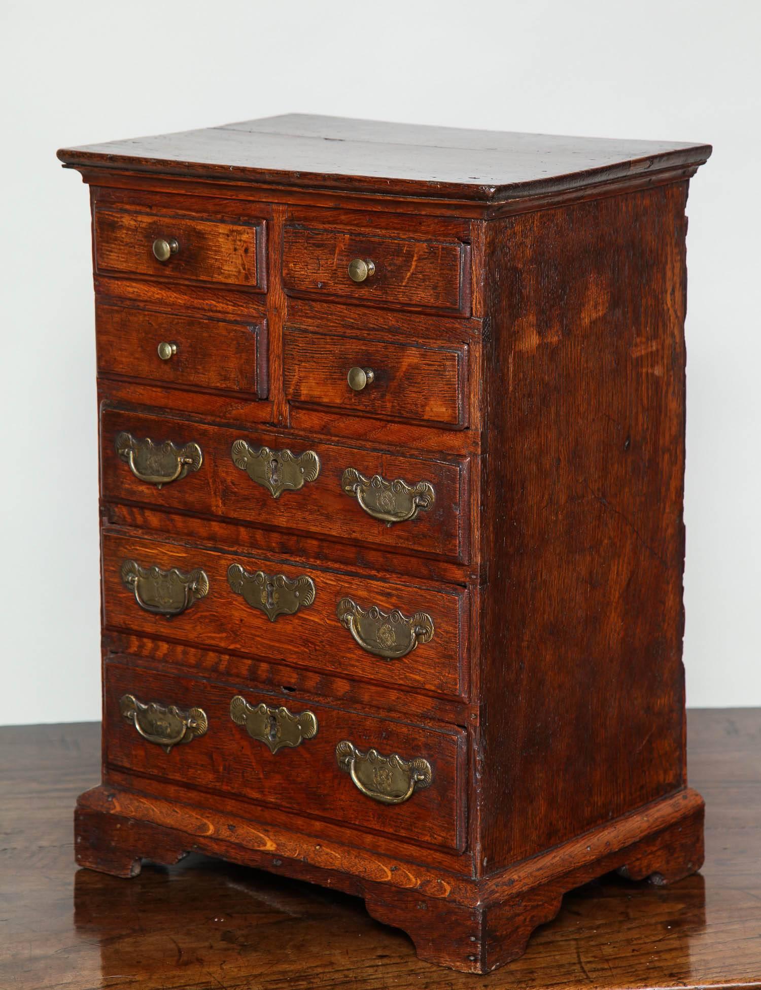 Charming and unusual early 18th Century Welsh tall chest having four small over three larger drawers all retaining their original brasses (the larger ones with etched backplates and wrought iron locks), standing on original bracket base, the whole