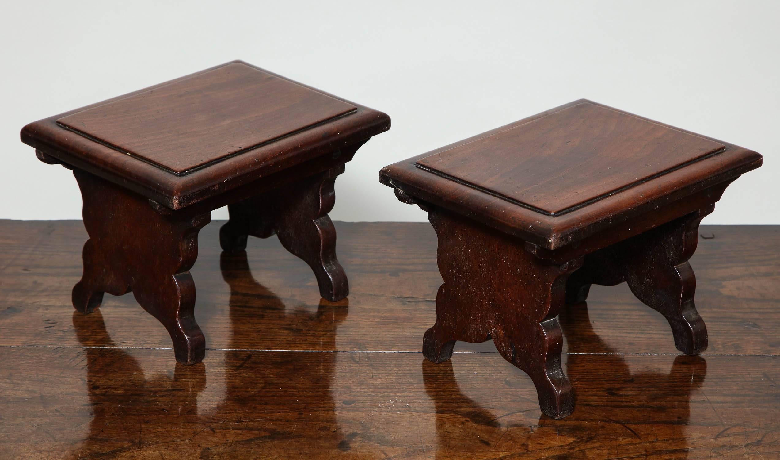 Very fine and rare pair of George II period mahogany dresser stools, the single board tops of dense mahogany with thumb molded edge over scalloped trestle ends with boarded sides.
Very attractive and useful in their own right, dresser stools have