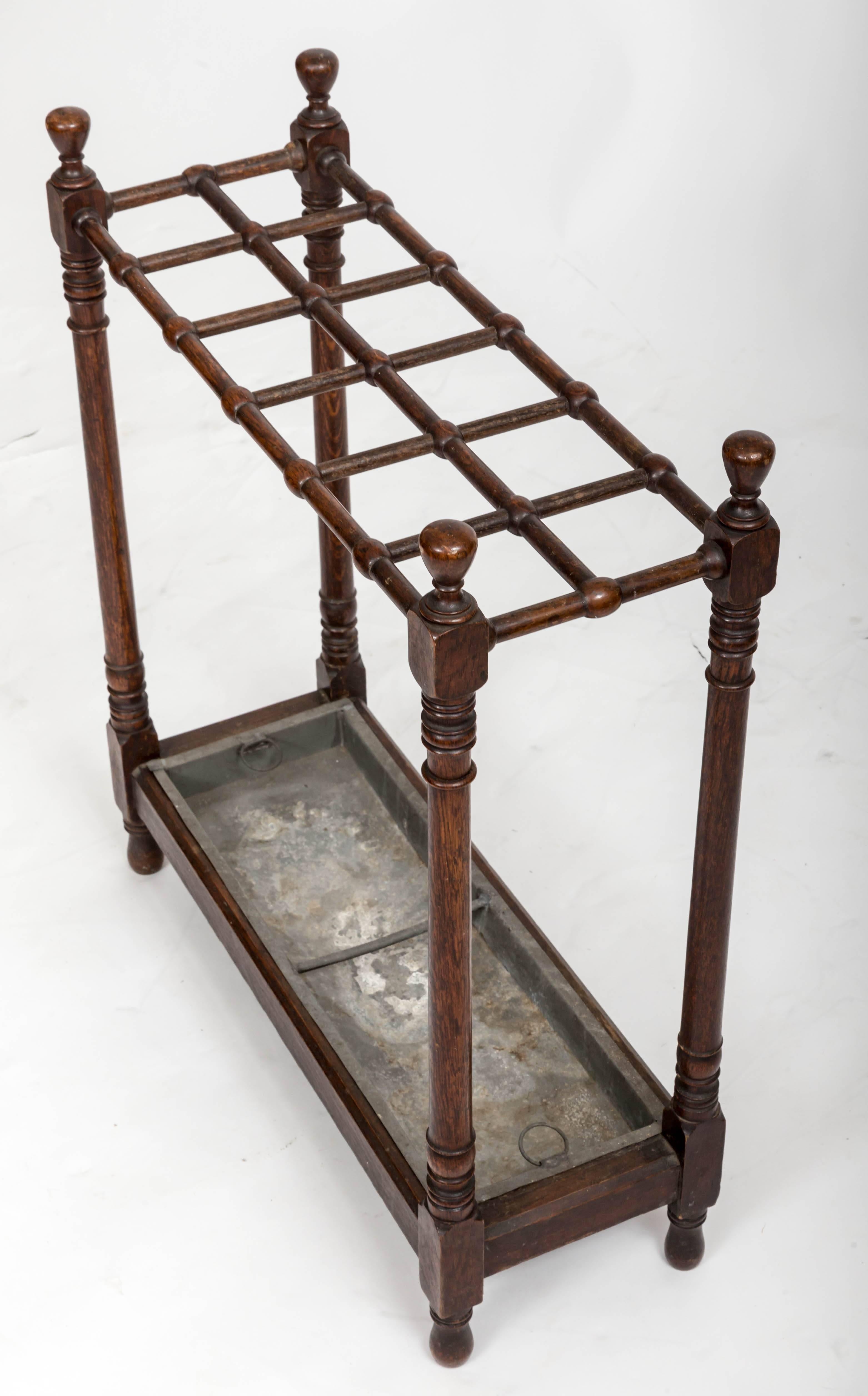 Twelve stick umbrella stand with turned wooden frame and original drip tray.