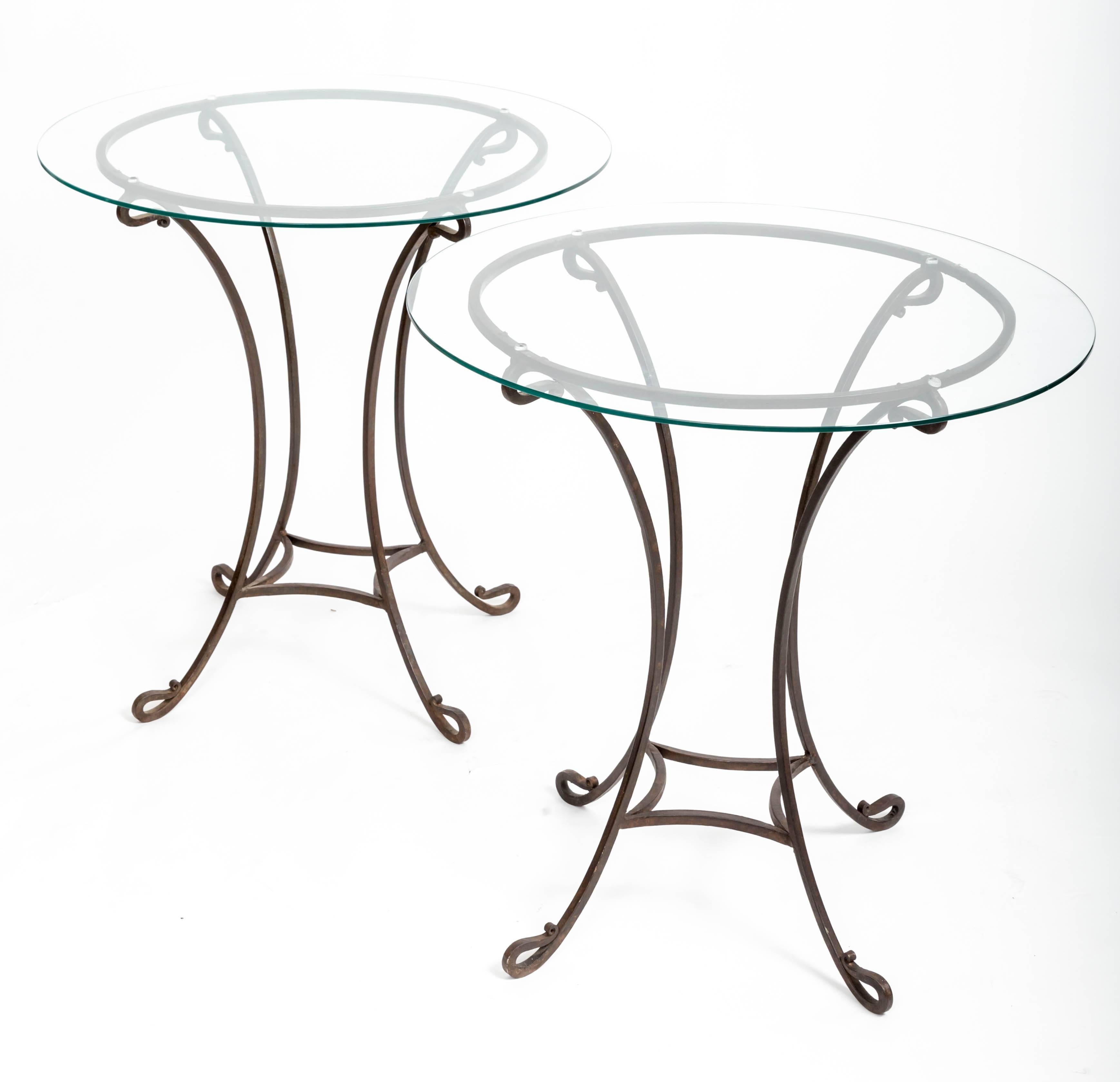 Pair of hand forged iron bases with scrolled feet and glass tops. Great as bedside tables. Can easily support two larger glass tops if desired. Measure: 30-32