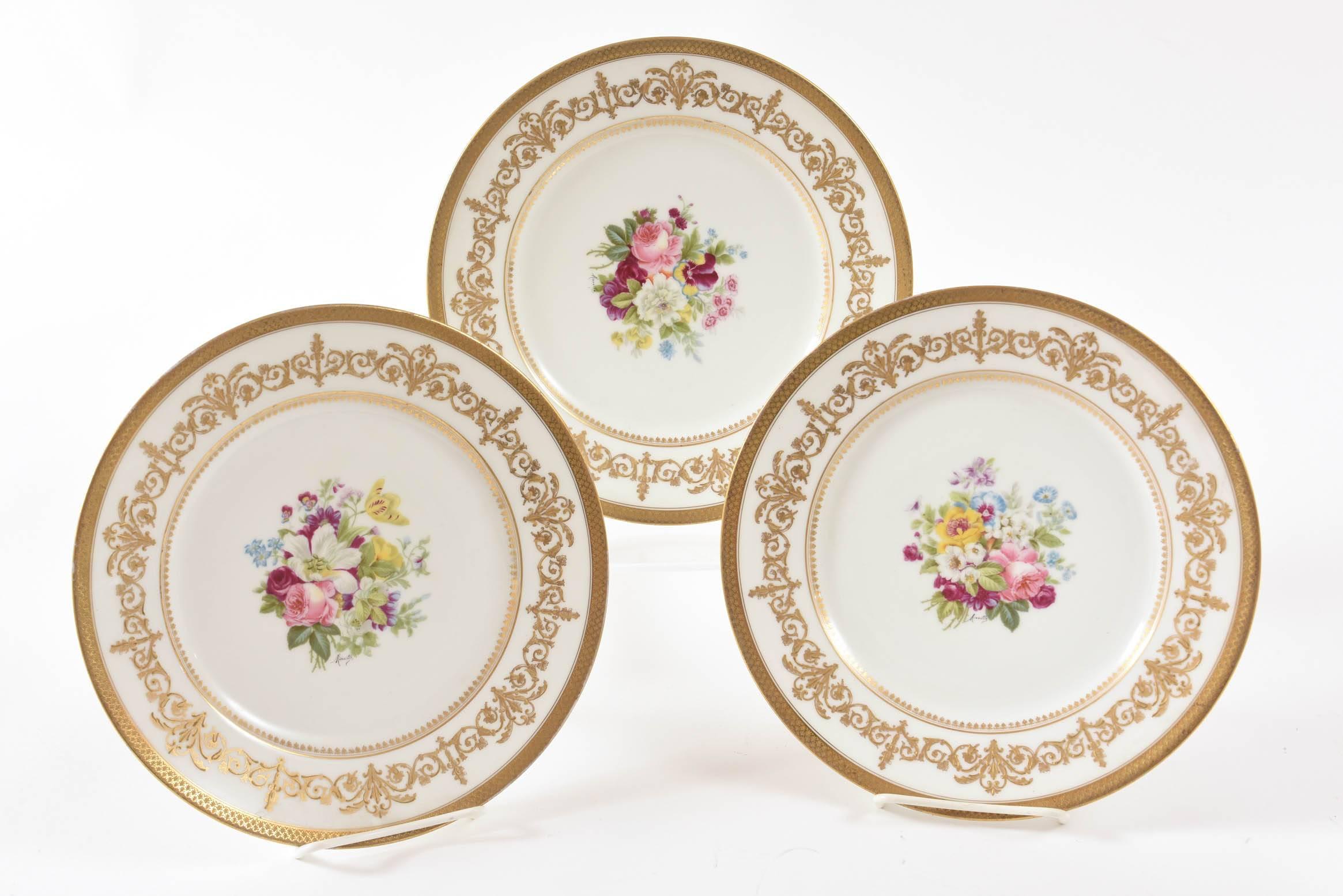 A beautiful hand-painted and artist signed set of plates by Charles Ahrenfeldt, Limoges and signed by Mireille. Each plate has a different selection of hand-painted flowers in the center and an elaborately decorated gilt collar finished with an acid