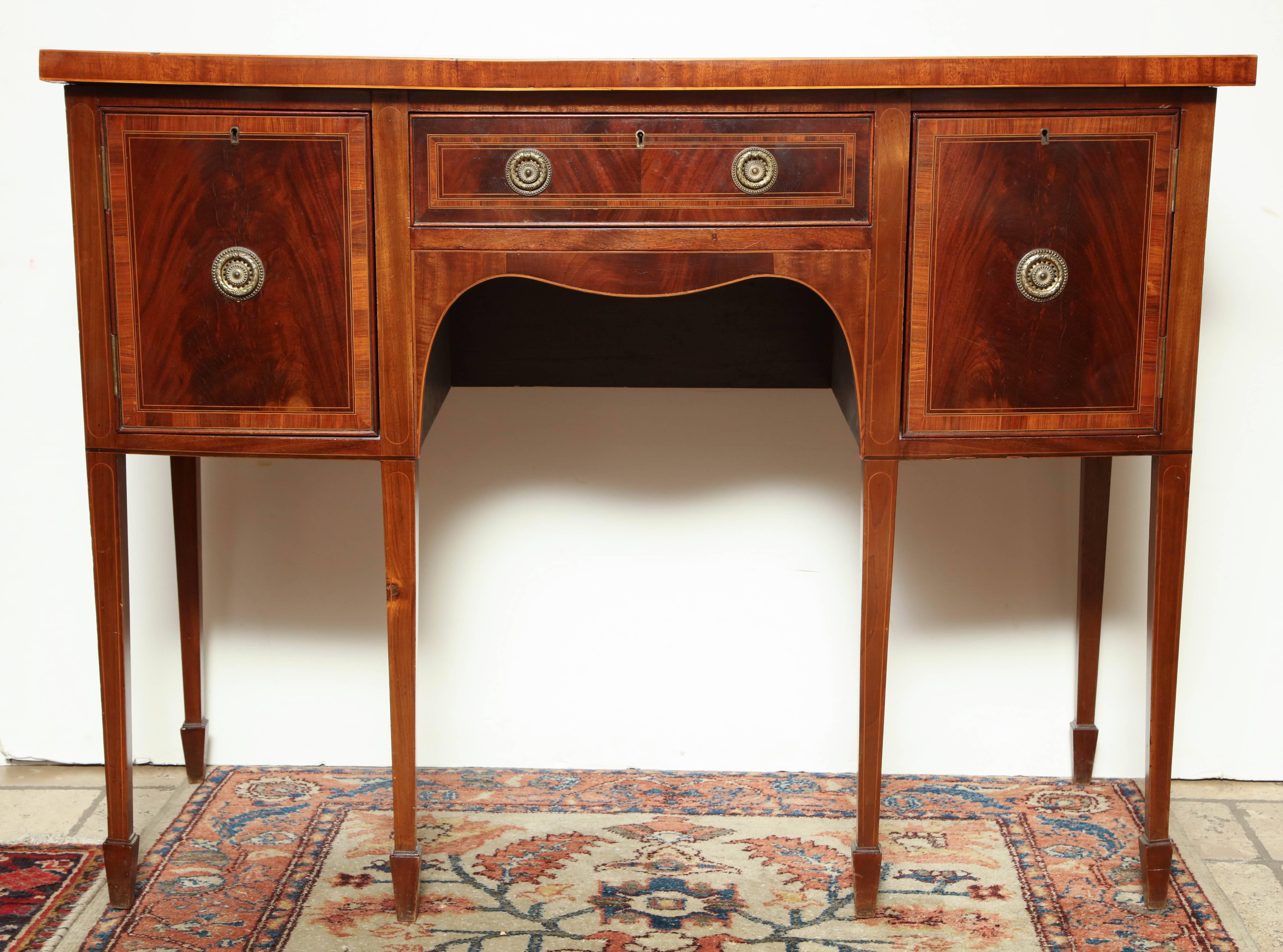 George II mahogany bow front side board with satinwood crossbanding and square tapered legs on spade feet.