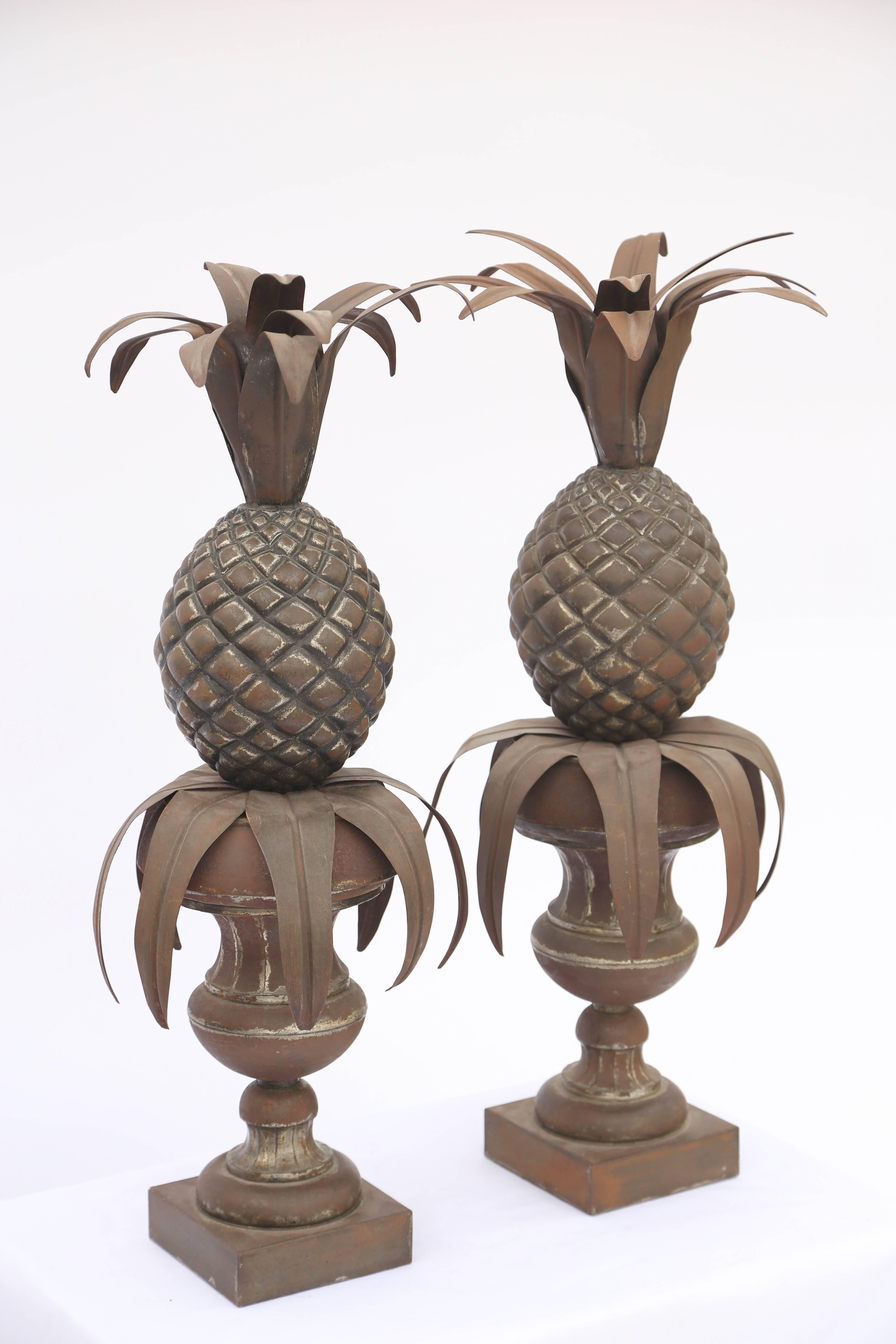 Pair of table decorations, of metal, having a distressed finish, each fashioned as a leafy pineapple, set upon a classical fluted urn, on round foot and square plinth. Can be made into lamps, if desired.

Stock ID: D2707.