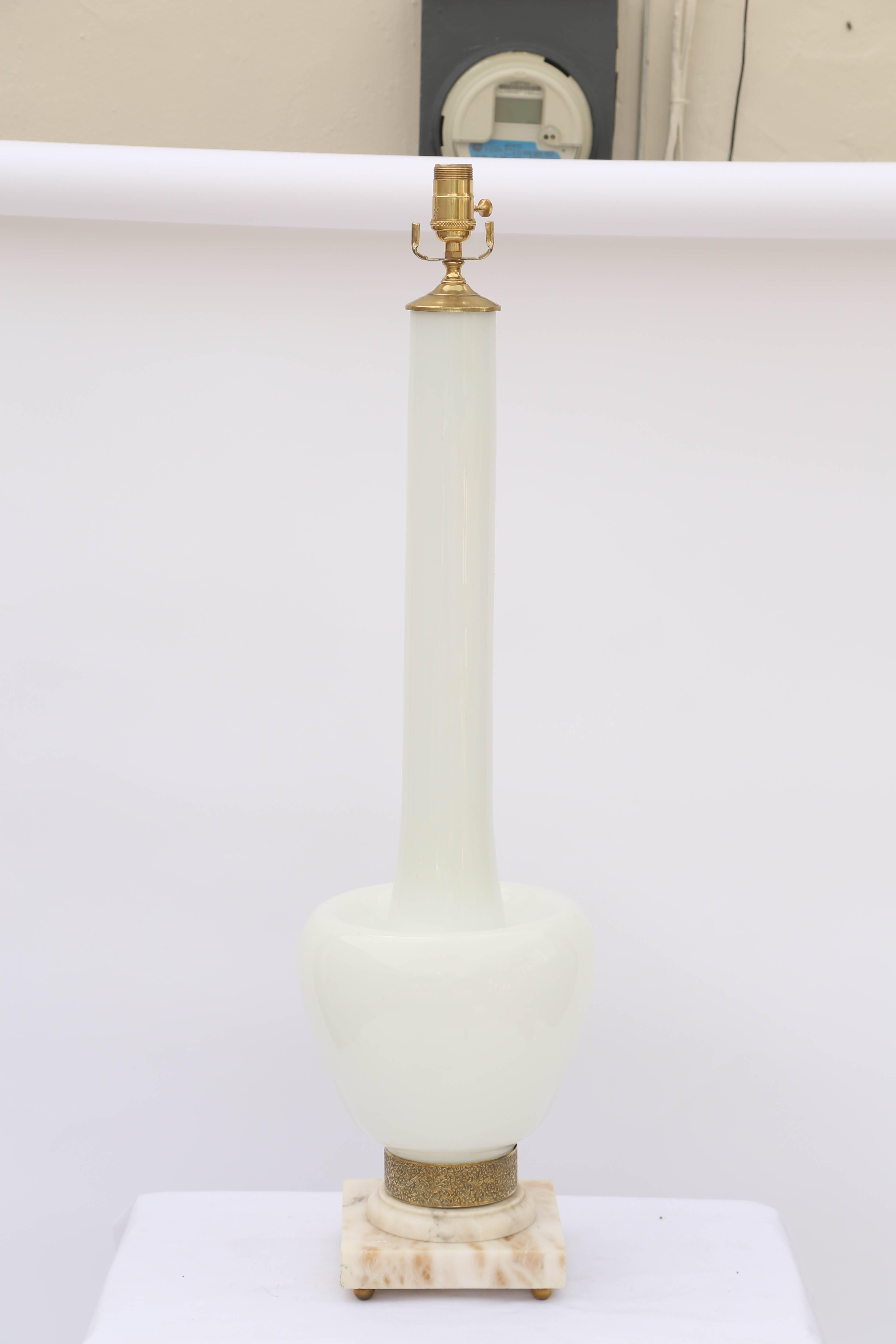 Single vase lamp, of handblown, frosted glass, in a stylized bottle form with extended neck, on round foot, wrapped in foliate brass repoussé collar, on graduated alabaster base, raised on ball feet.

Stock ID: D6382.