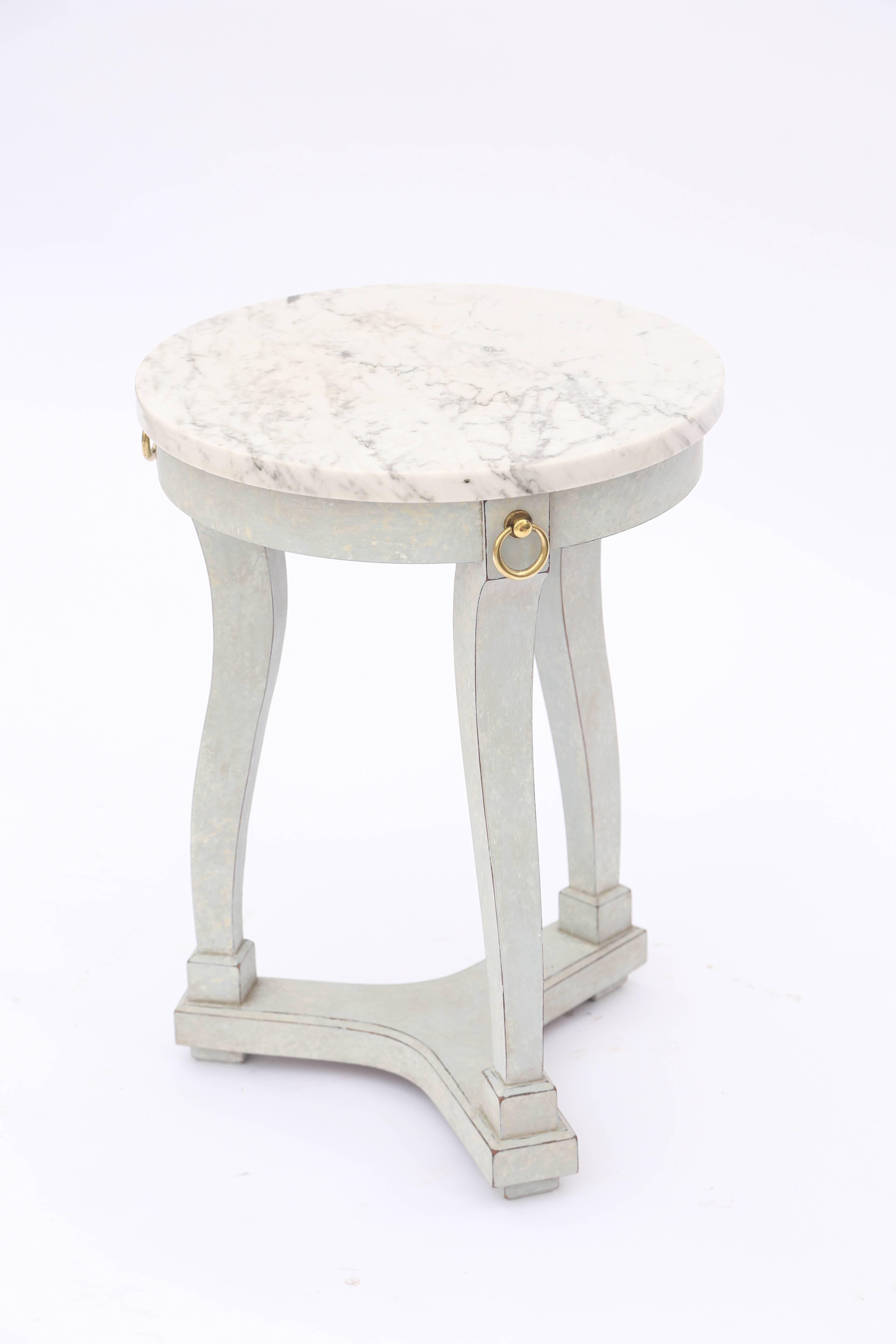 Guéridon side table, having a round top of marble, on painted base with natural wear, raised on curving, square section legs, each headed with a brass ring, on concave tripartite base.

Stock id: D6404.