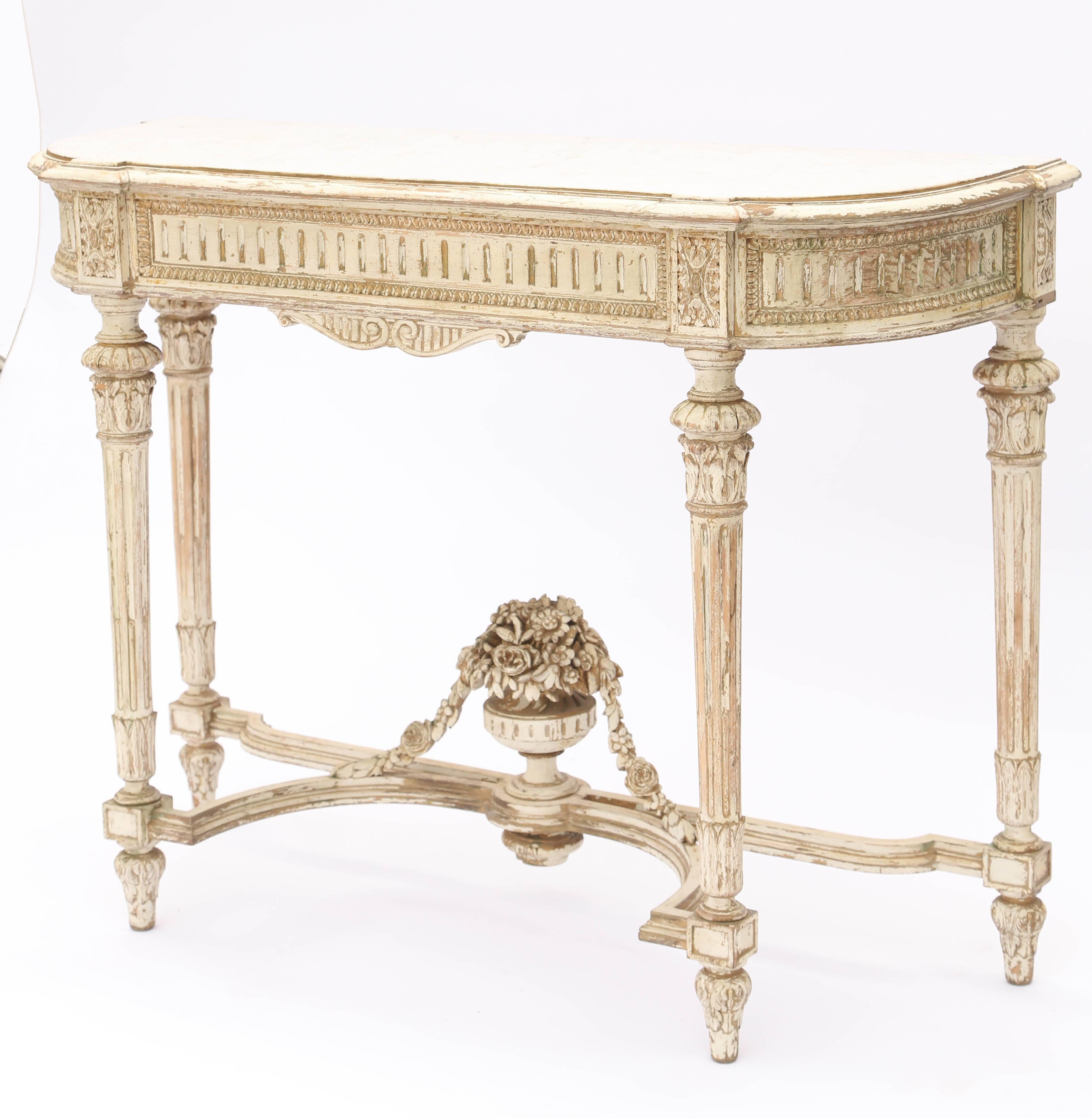 Console table, having a D-shaped top of white marble, in molded frame, on painted table base with natural wear, its fluted apron framed by gadrooning, and separated by rosette blocks, raised on acanthine-headed, round, tapering, fluted legs, joined