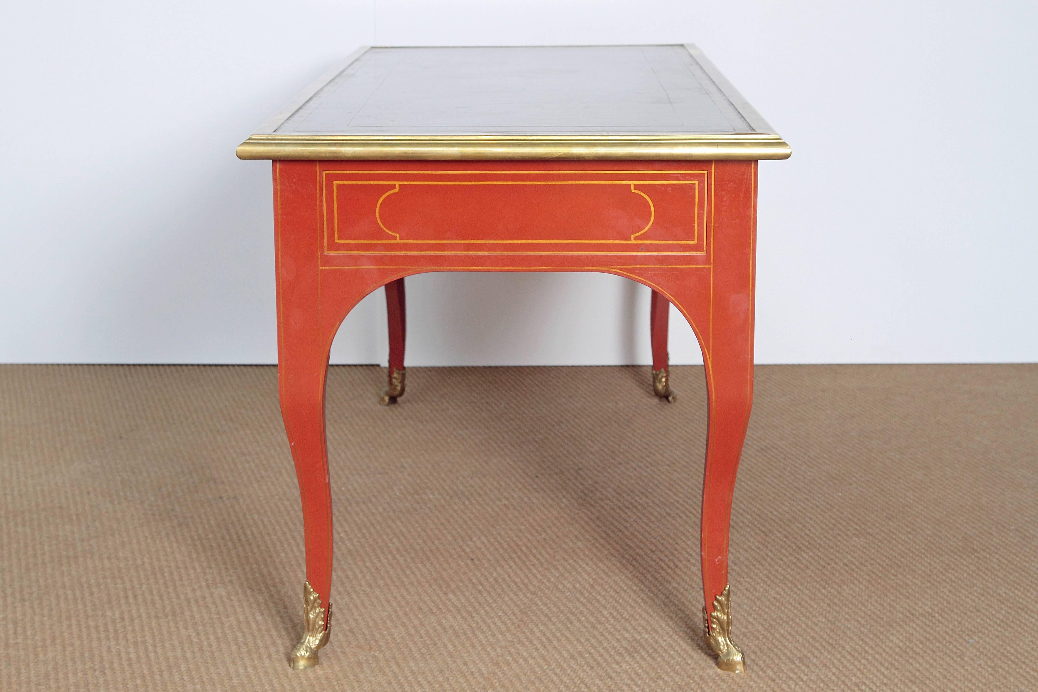an orange lacquered Louis XV reproduction writing desk / bureau plat by Baker Furniture Collector's Edition reproduced from a French original circa 1720, with rich leather top / writing surface, hand tooled with gold borders, gilt striping and Sabot