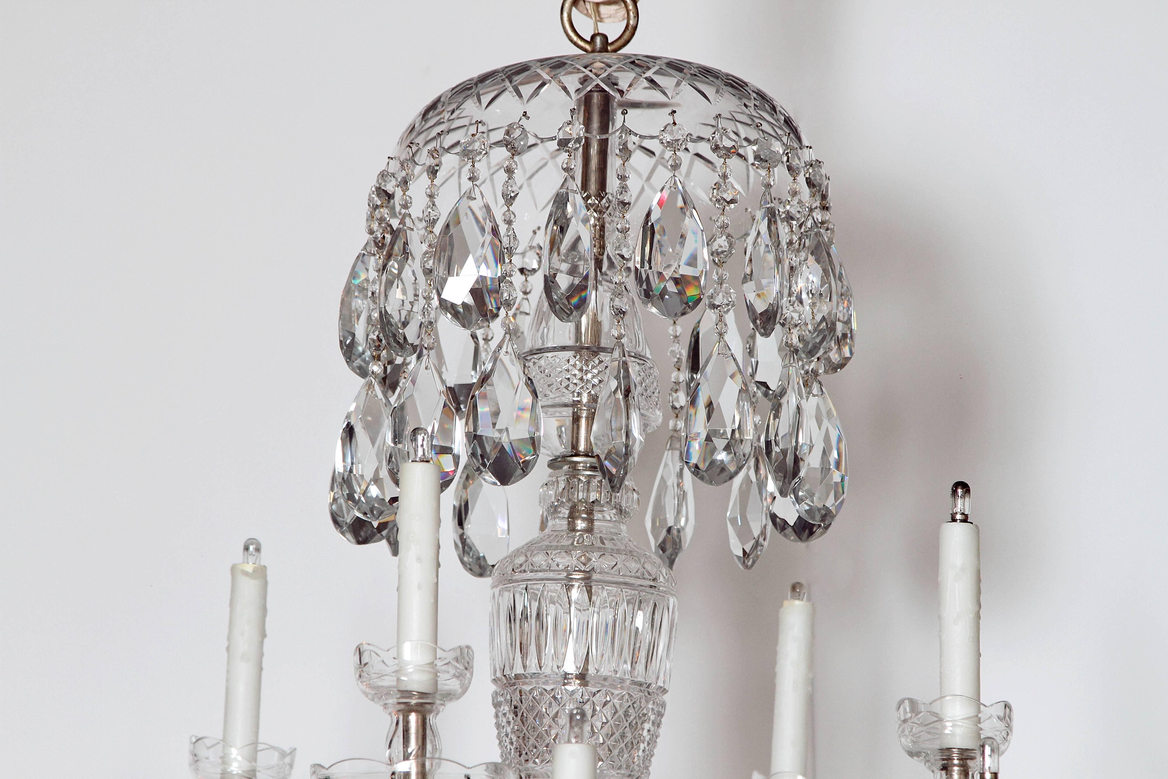 A large twelve-light Georgian style lustre / cut crystal chandelier dripping with crystals from both the top and the bottom with a central cut crystal urn form body.