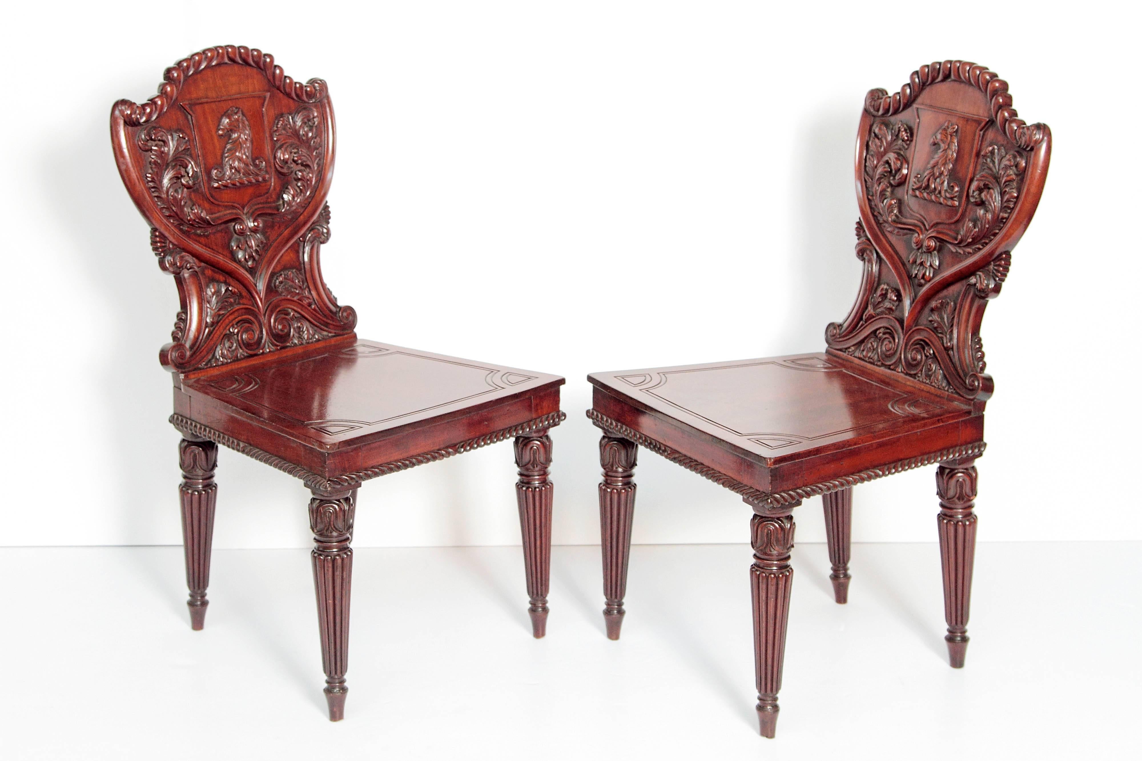 A pair of English Regency mahogany shield back hall chairs. Carved with erased muzzled bear's head. Acanthus leaves and Flemish scrolls. Round tapered reeded legs, circa 1810.