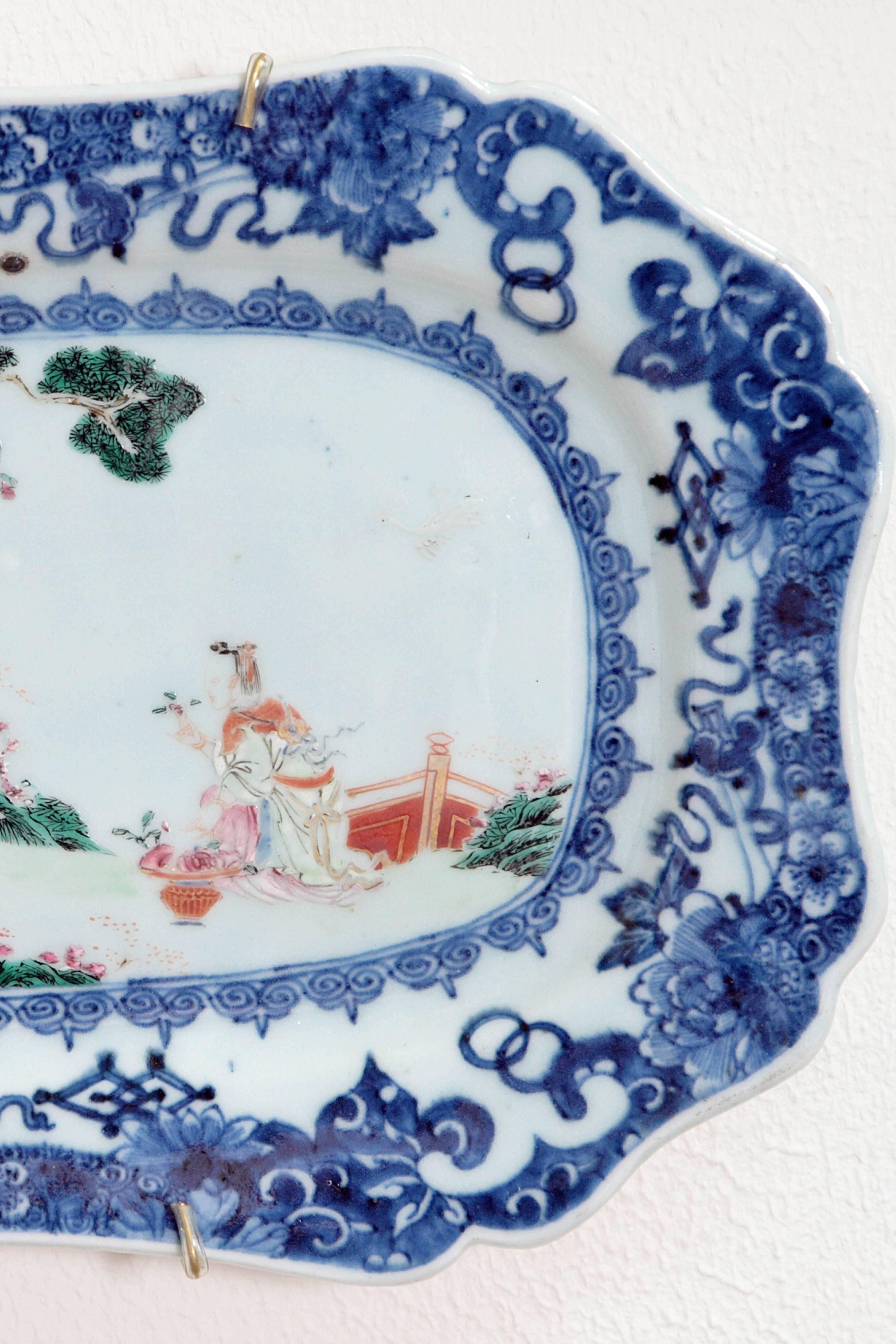 A mid-18th century group of four hand-painted porcelain platters, Chinese Export, octagonal form with foliate blue border, central scene depicts a pair of Chinese beauties with flower baskets, one carried over the shoulder on a long slender pole, in