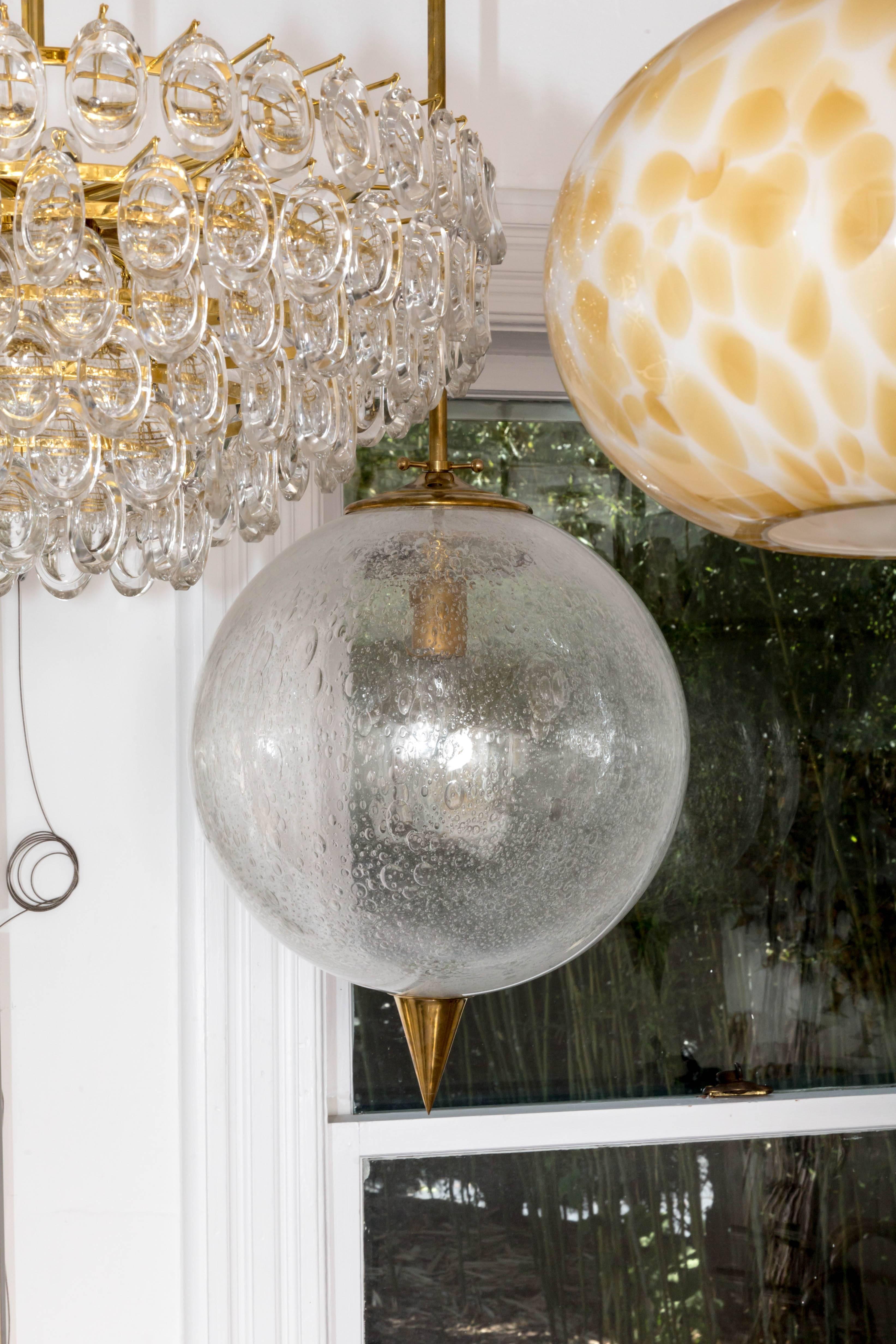Spherical clear glass pendant with inclusive air bubbles and brass details
by Barovier.