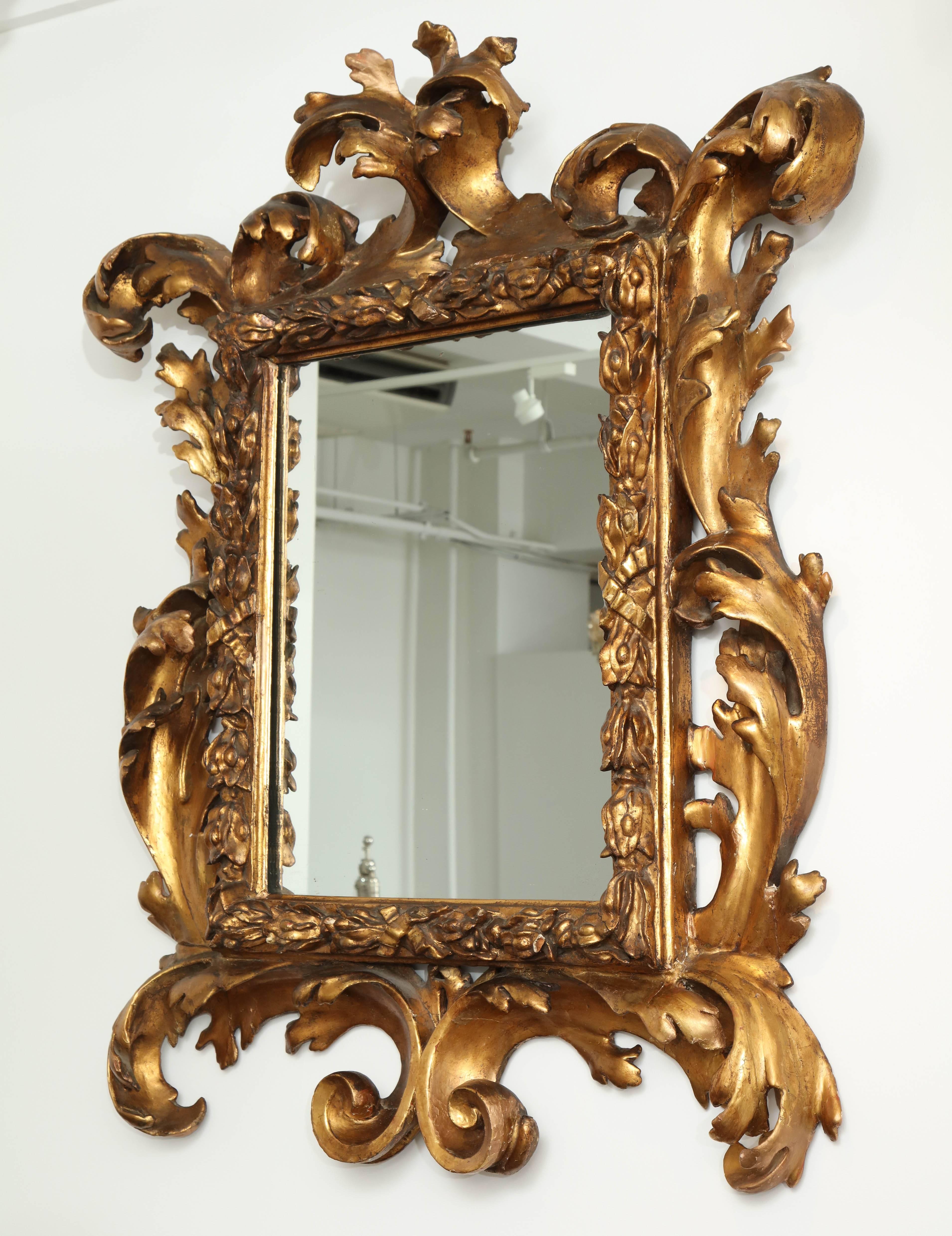 This 18th century Italian large Baroque gilded mirror is a true statement piece.
The elaborately carved gilded frame with open scroll work and acanthus leaf decoration is in great condition with minimal restorations.