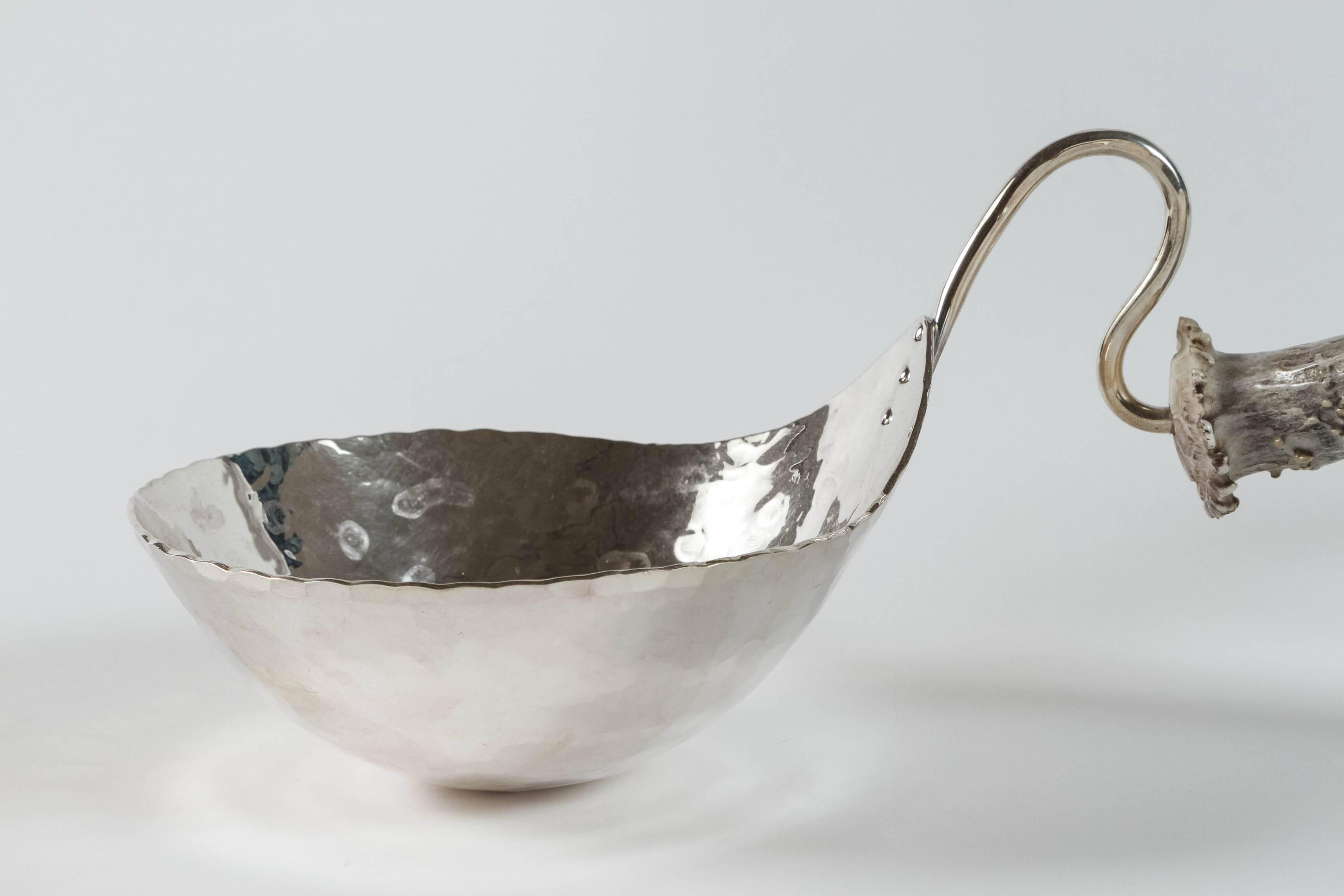 This nut bowl is made out of silver and features an antler handle. Ben Caldwell creates by hand copper and sterling silver pieces, bowls, trays and sculptures using traditional smithing techniques. The hand-wrought texture covering every surface is