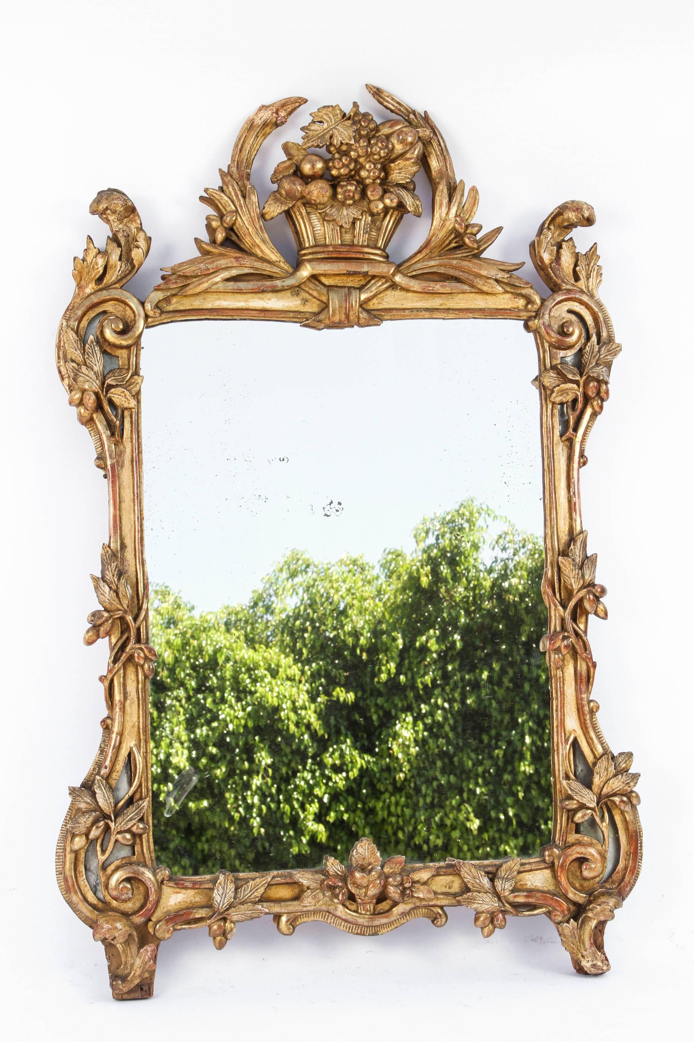 18th century, French Regence mirror with original glass plate. The giltwood frame is finely carved with a fruit basket motif.