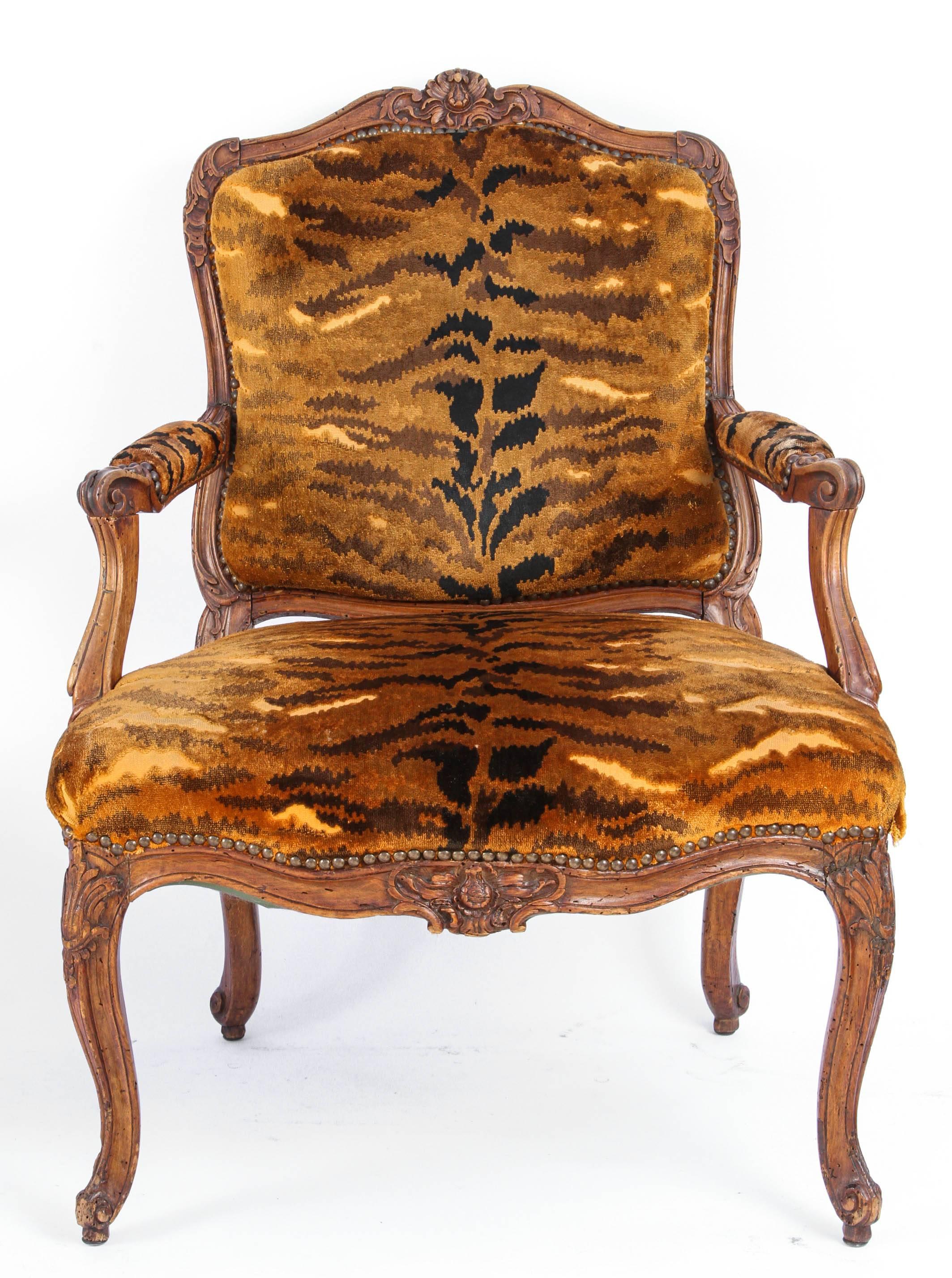 Similar Pair of 18th century French Regence carved walnut armchairs with silk velvet leopard print upholstery and nailhead detail. Each chair is slightly different in size.