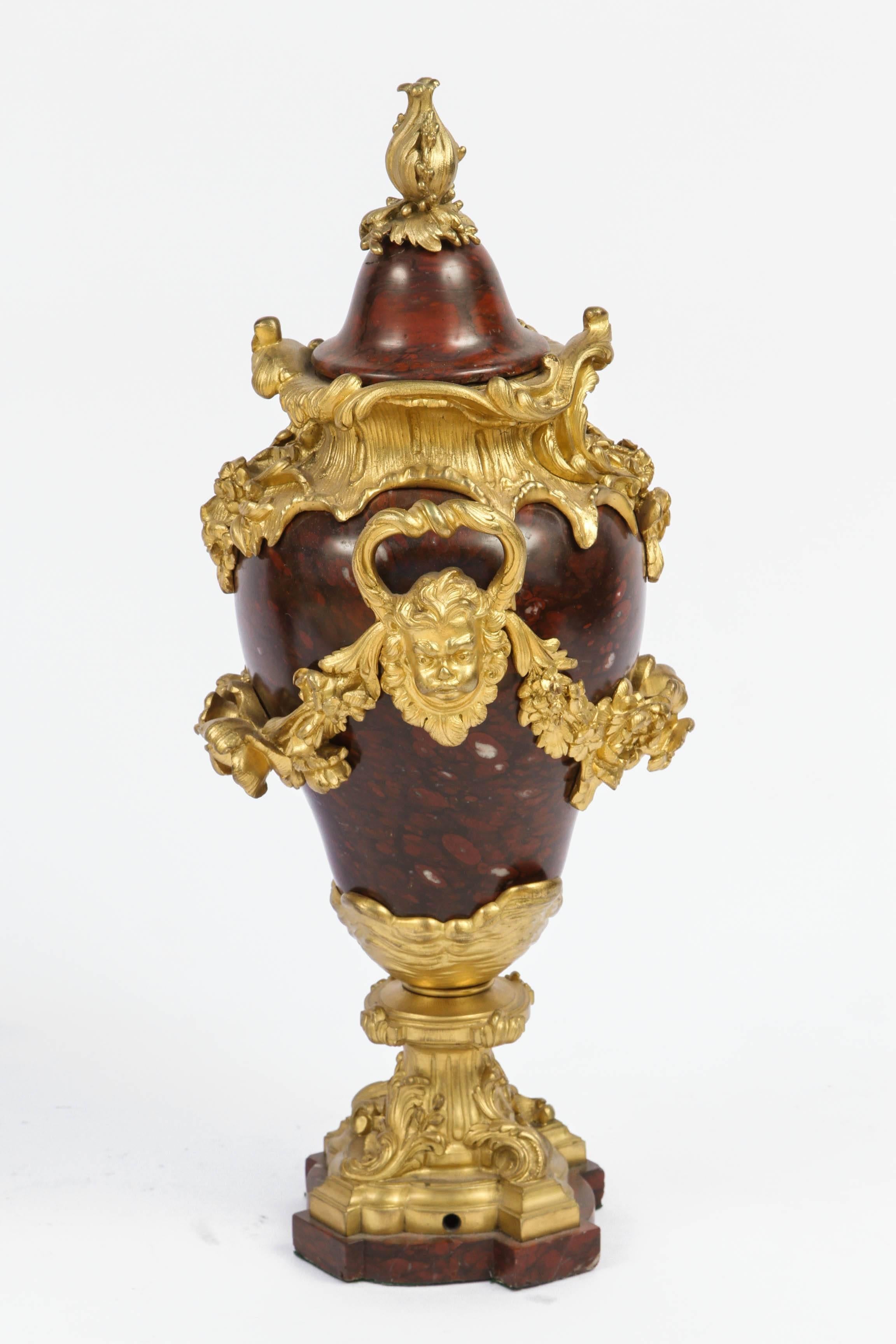 Pair of 19th century French rouge marble urns with finely chased doré Bronze and cherub head motif.