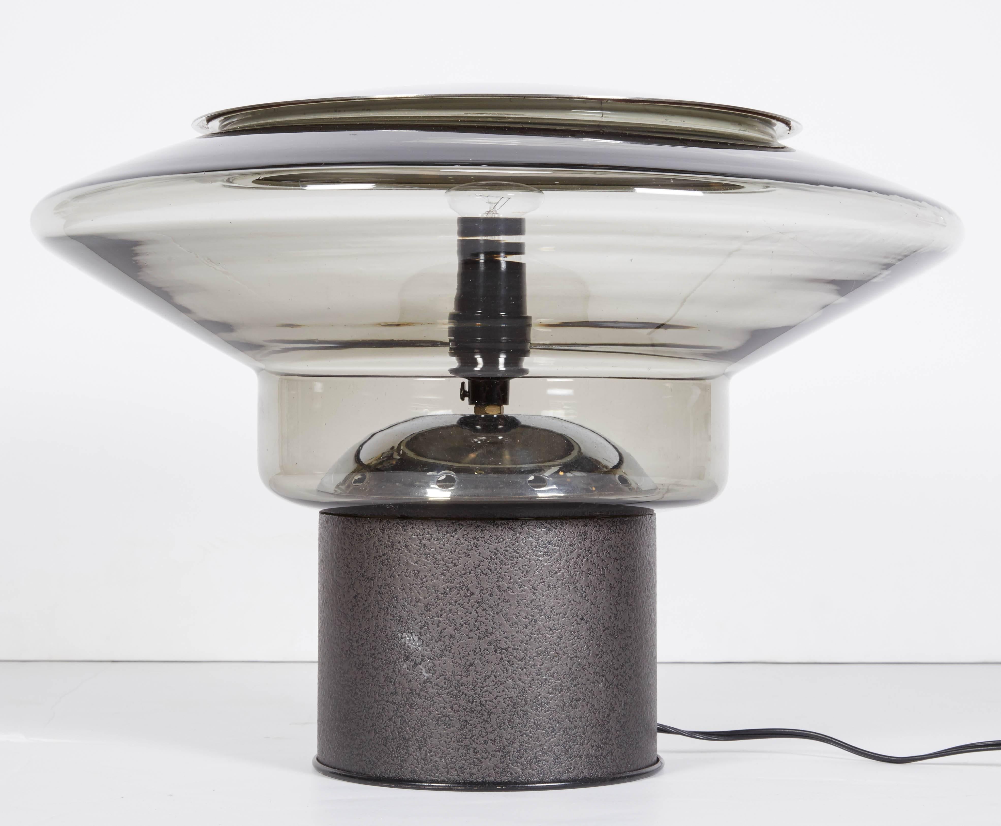 A statement piece of Italian modern design, circa 1970. This table lamp is a sculpture in glass, metal and light in table lamp form. The large shade is handblown Murano glass in pale grey. It rests securely atop a charcoal grey black textured enamel