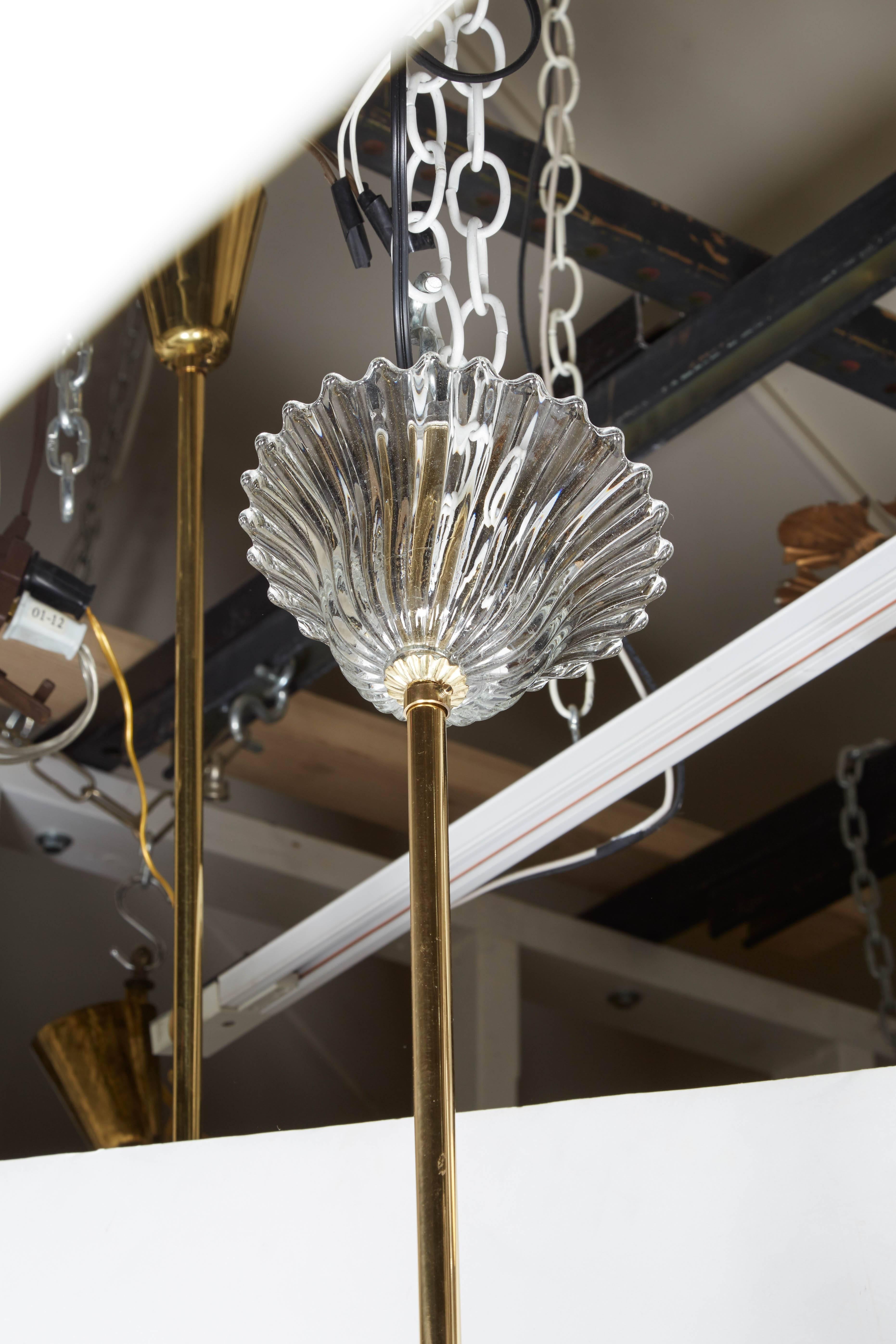 Perfect for a light and airy feeling room is this Italian, 1950s chandelier. The body of the chandelier is polished brass and supports 5 arms of light. Hand formed clear glass fronds extend from the central bowl. Clear blown glass bobeche sit atop