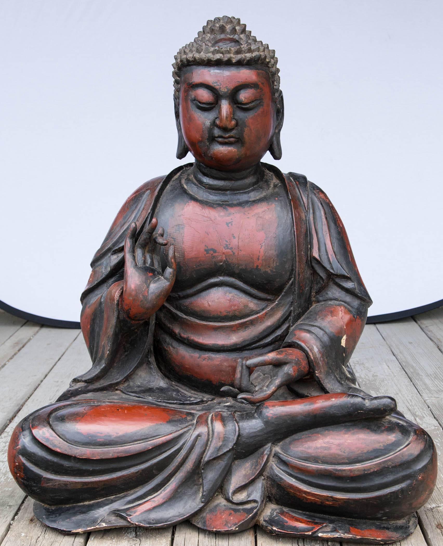 This large Buddha is of carved wood covered in lacquer. His hands in the protective gesture. Hands carved separately and attached with dowels.