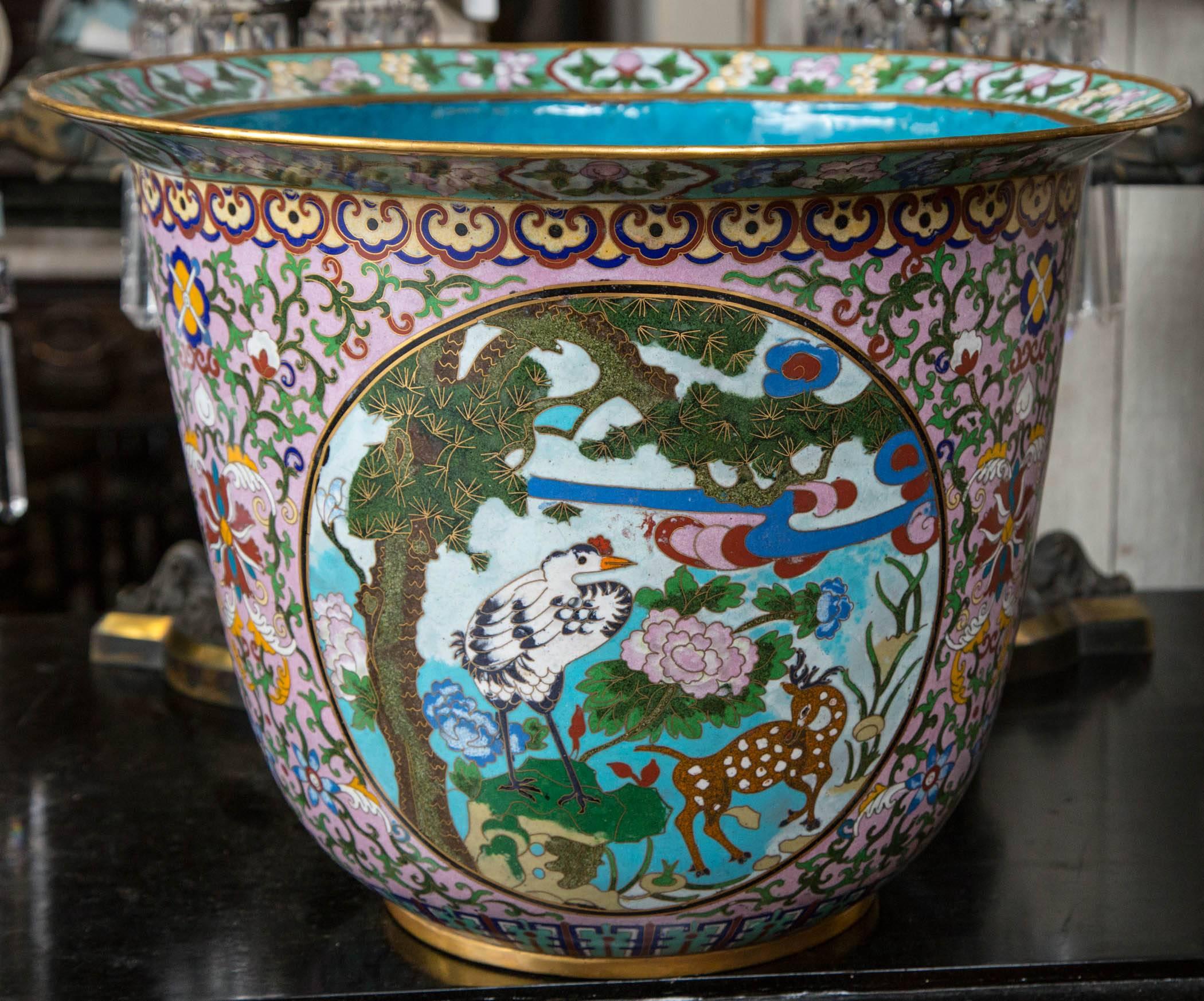 This multi colored pair of cloisonné planters are each decorated with three round scenes of a crane and a fawn in a forest setting. The interior is solid sky blue with a band of flowers. Chinese symbols decorate the bodies apart from the forest