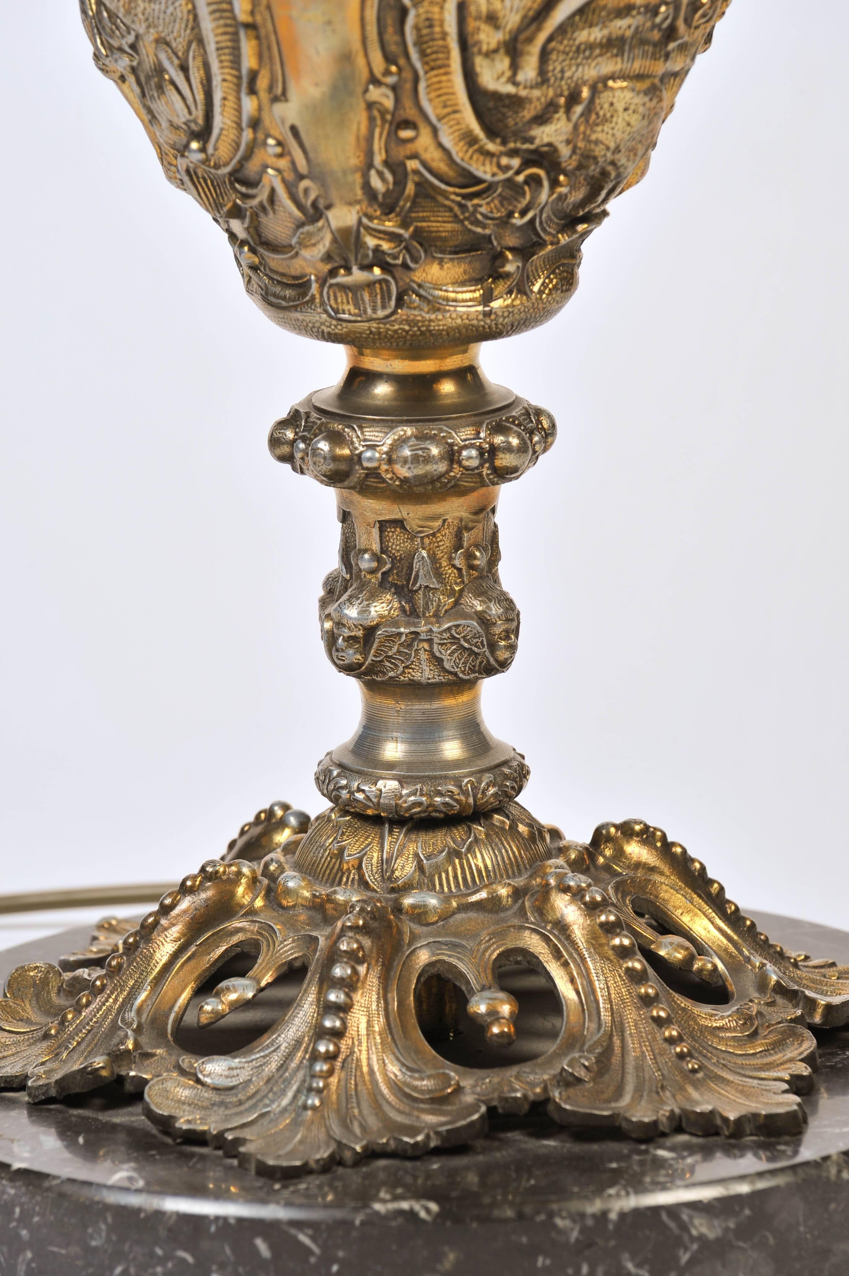 The vase shaped lamp with stylized female torso handles above a double classical scene on a stylized foliate foot and circular marble base.
The whole cast with foliate and floral designs in the classical manner.