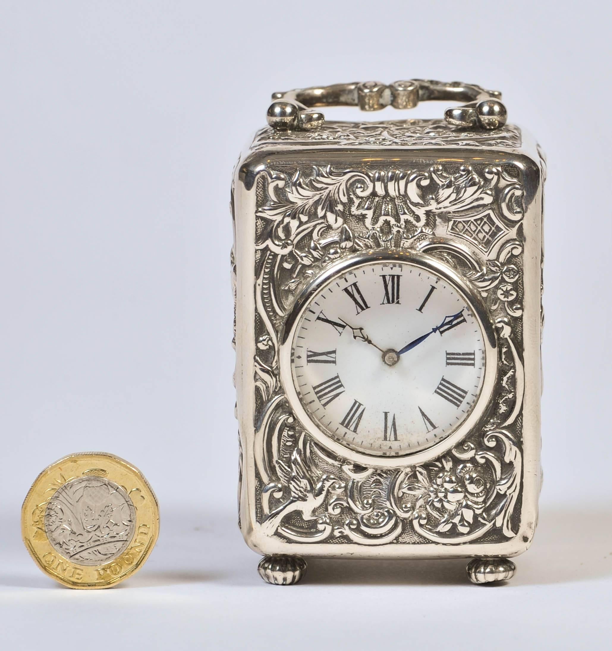 A charming diminutive carriage clock, the repoussé case with scroll, foliate and bird motifs, hallmarked William Comyns of London, 1896.
  