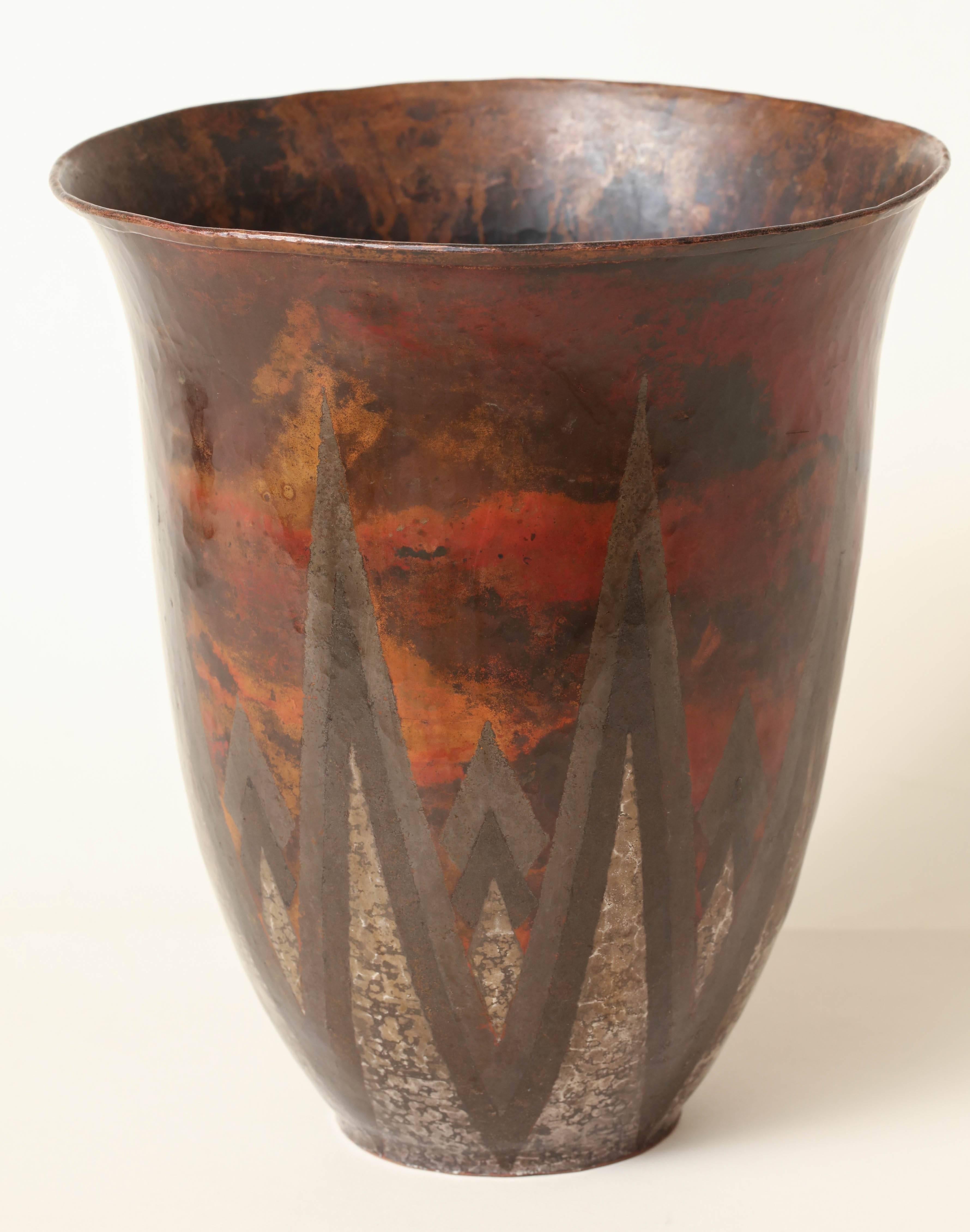Measures: 9 1/4'' high; 8 1/8'' wide

This dinanderie copper and silver vase has a martele oblong body with out-turned collar. The decor is of stylized foliage in herringbone gray and ochre on a red background. 

Impressed CL-Linossier