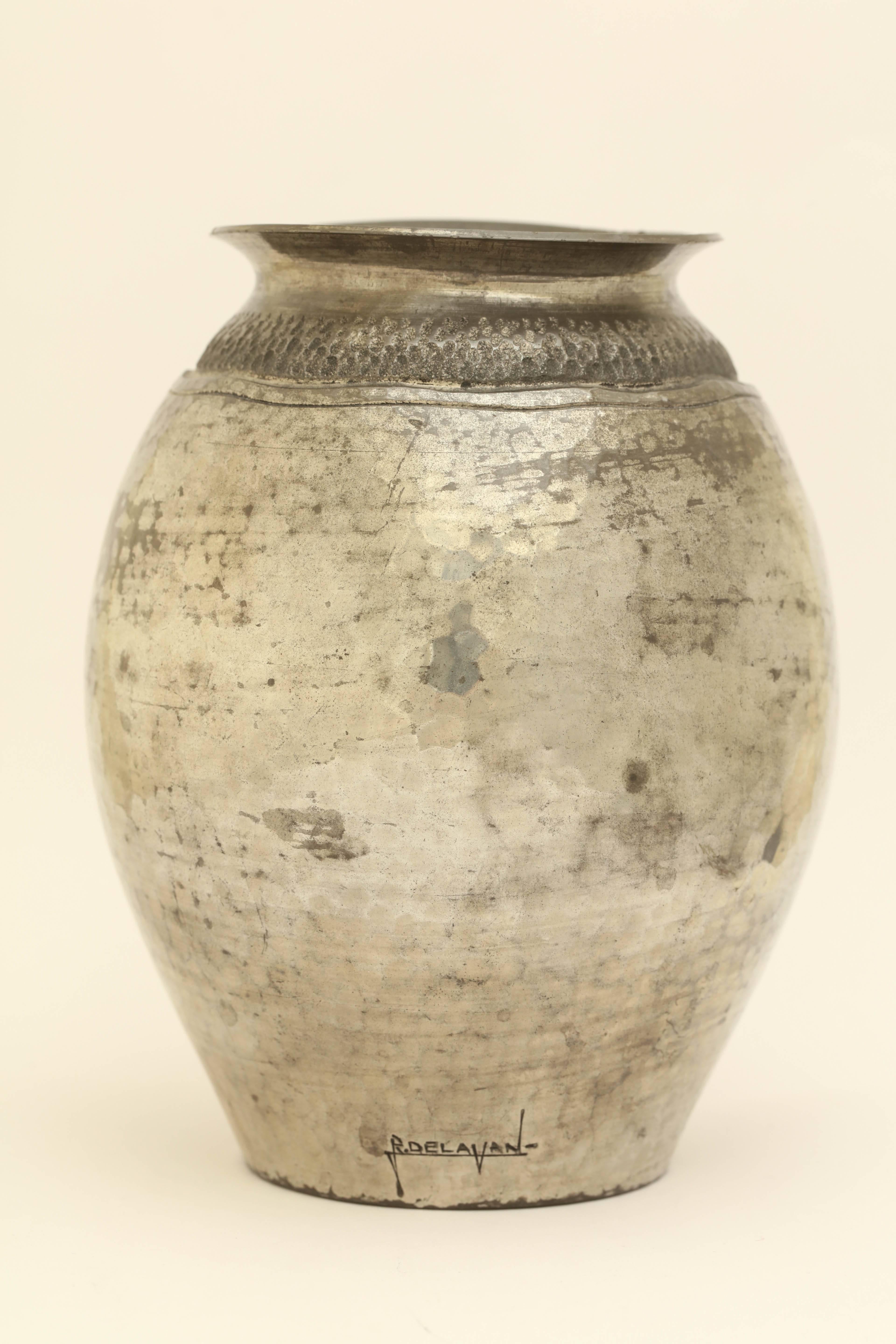 Hand-wrought pewter dinanderie martele ovoid vase with striated grey ring over two wavy lines around the neck.

Signed R. Delavan on the side/ impressed R DELAVAN/ DECORATEUR/ PARIS/ ETAIN D'ART and numbered 1338 underneath.