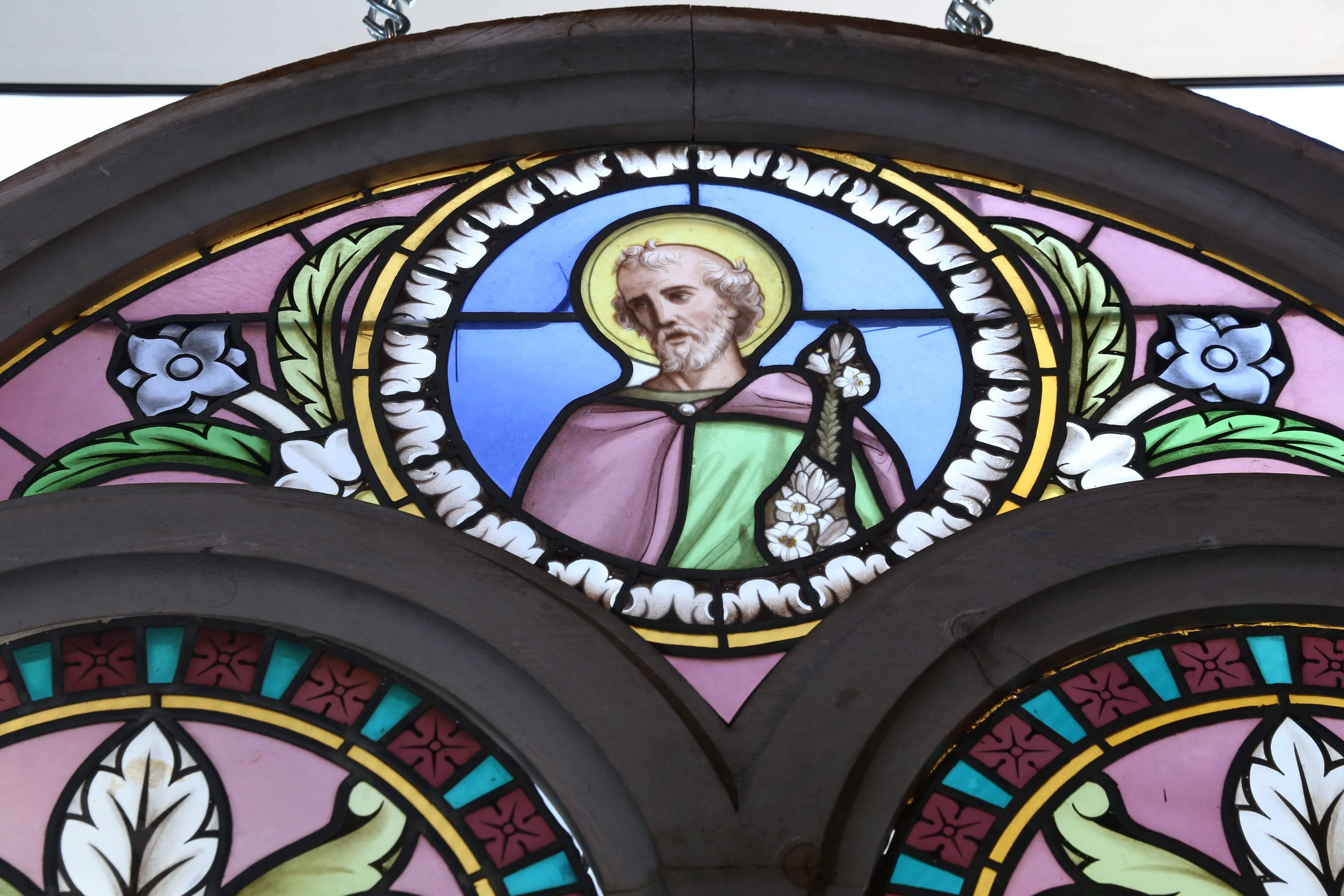 Religious stained glass window, depicting a disciple, set in wooden
Frame that has been painted a gray hue. Minor cracks; no serious
Problems. Very beautiful!