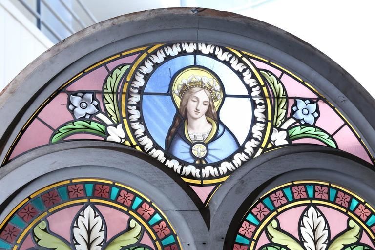 Magnificent pair of stained glass windows set in a wooden frame that
was painted in a gray hue. The colors are lavender, green and blue.
At the crest the Virgin Mary is depicted on one and Jesus is depicted
on the other. There are a few very