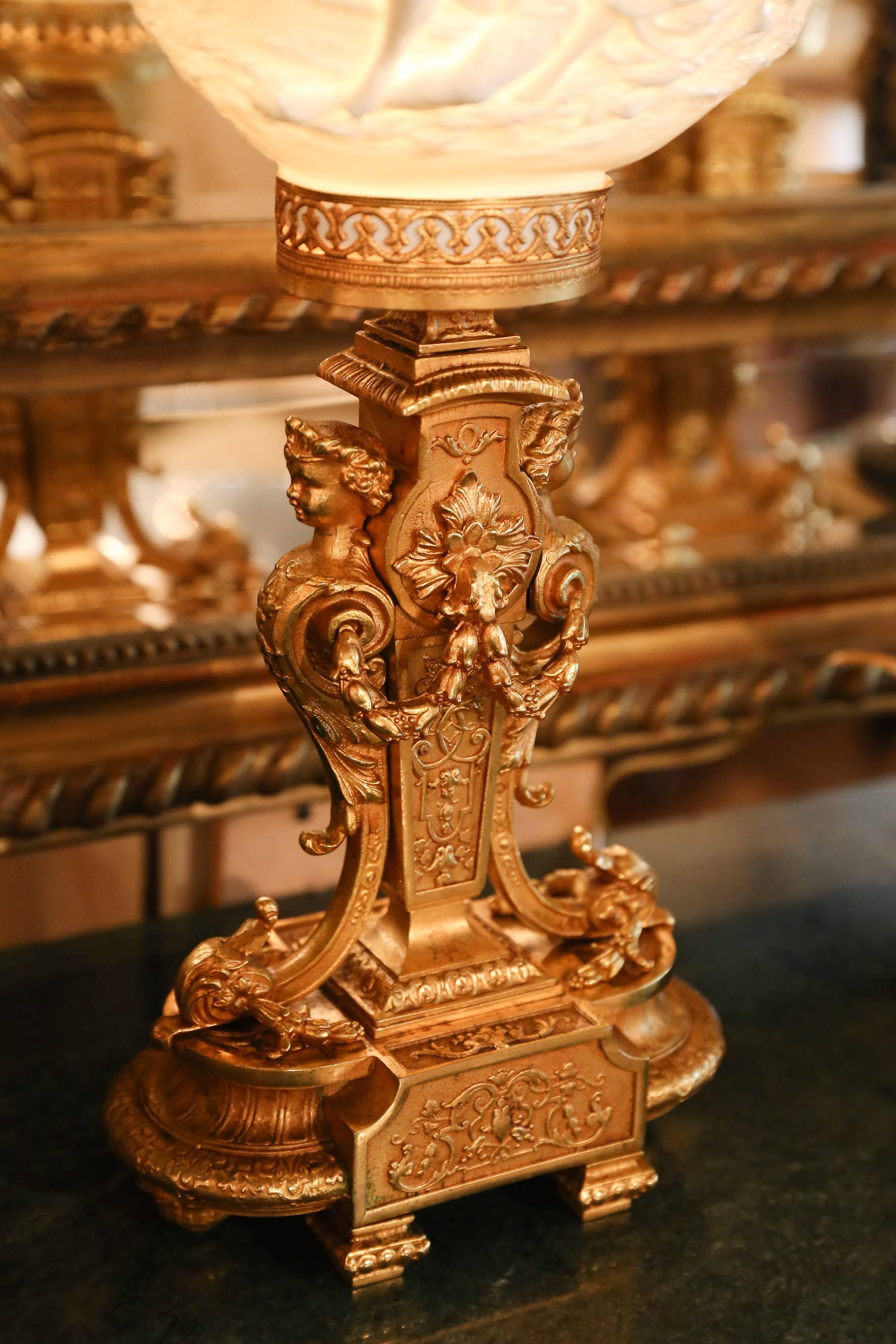 Pair of Italian porcelain and gilded bronze table lamps, Tiche porcelain shades
topped with gilt bronze flowers, showing low relief scene of courting couple
on one side, landscape with castle on opposing side, over gilt bronze base
decorated with