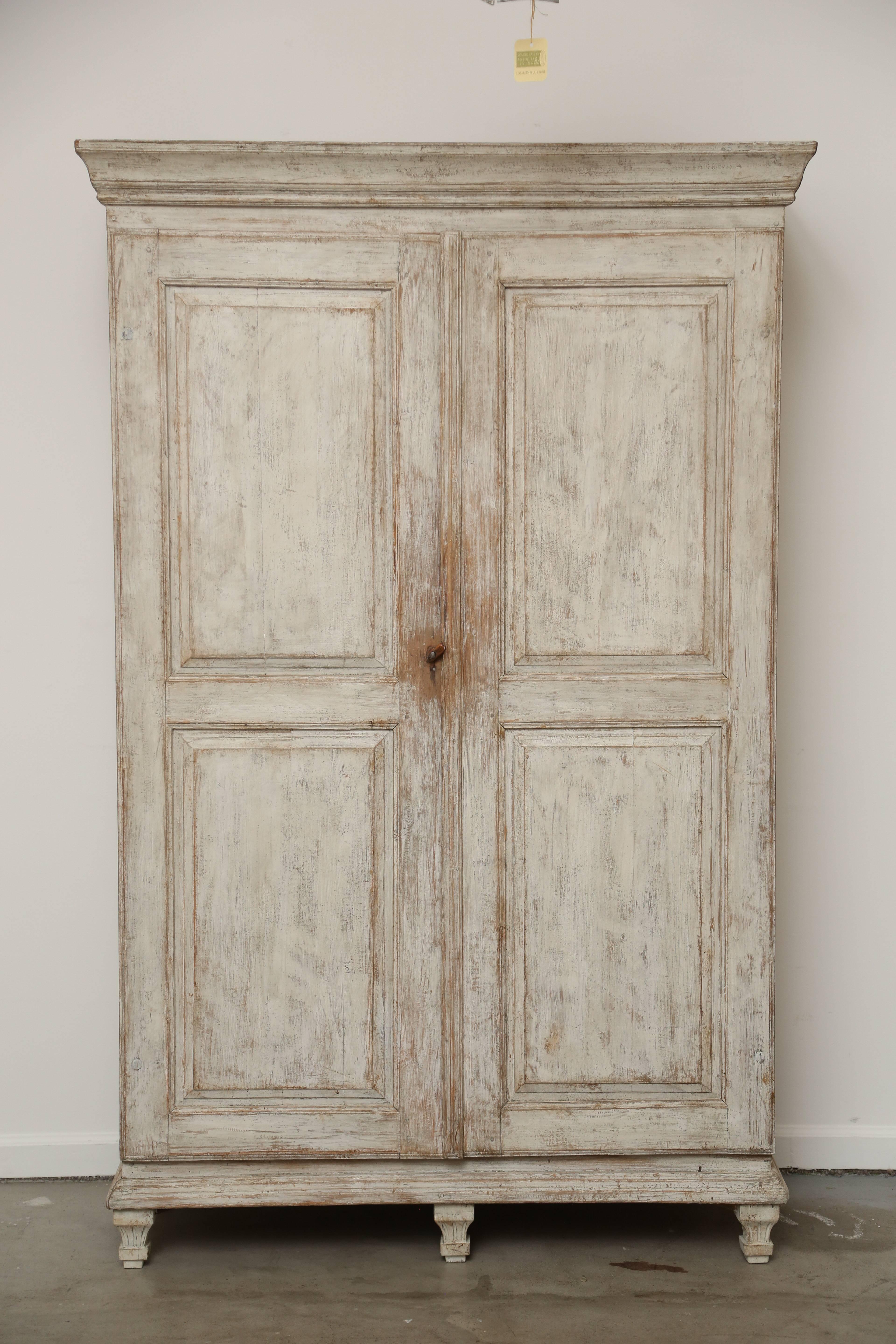 Antique Swedish Gustavian distressed painted beige Armoire/cabinet.
Very nice carved crown molding top cornice. Two full length raised panel
carved doors with original wood turn closure. Carved base with five carved
fluted tapered legs. Interior has