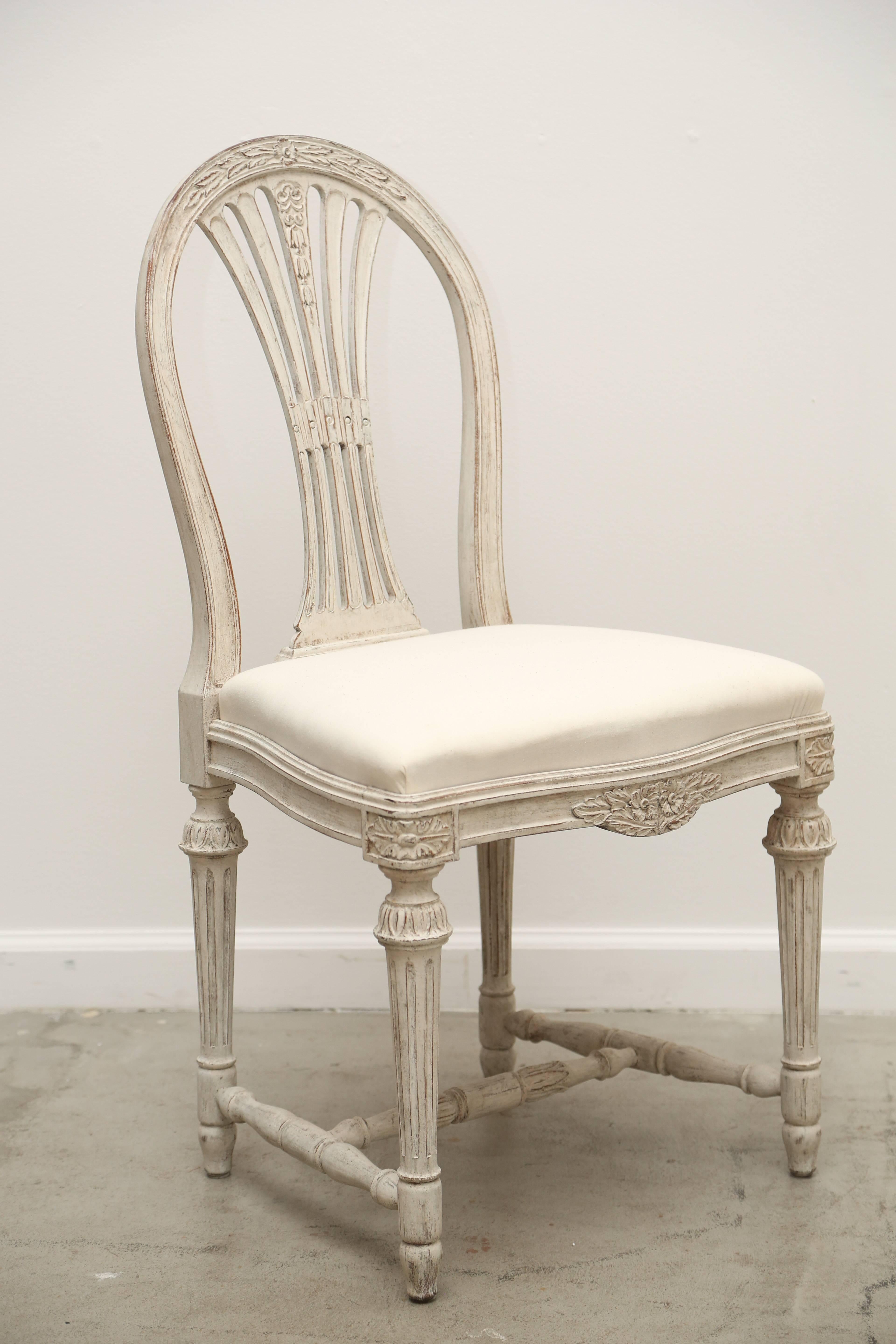 A set of ten antique Swedish Gustavian style painted dining chairs with arched 
backs with beautiful carved leaves and flowers, graceful slate openwork, drop in
shaped seats, carved lower apron with flowers and round fluted legs joined
by H-shaped
