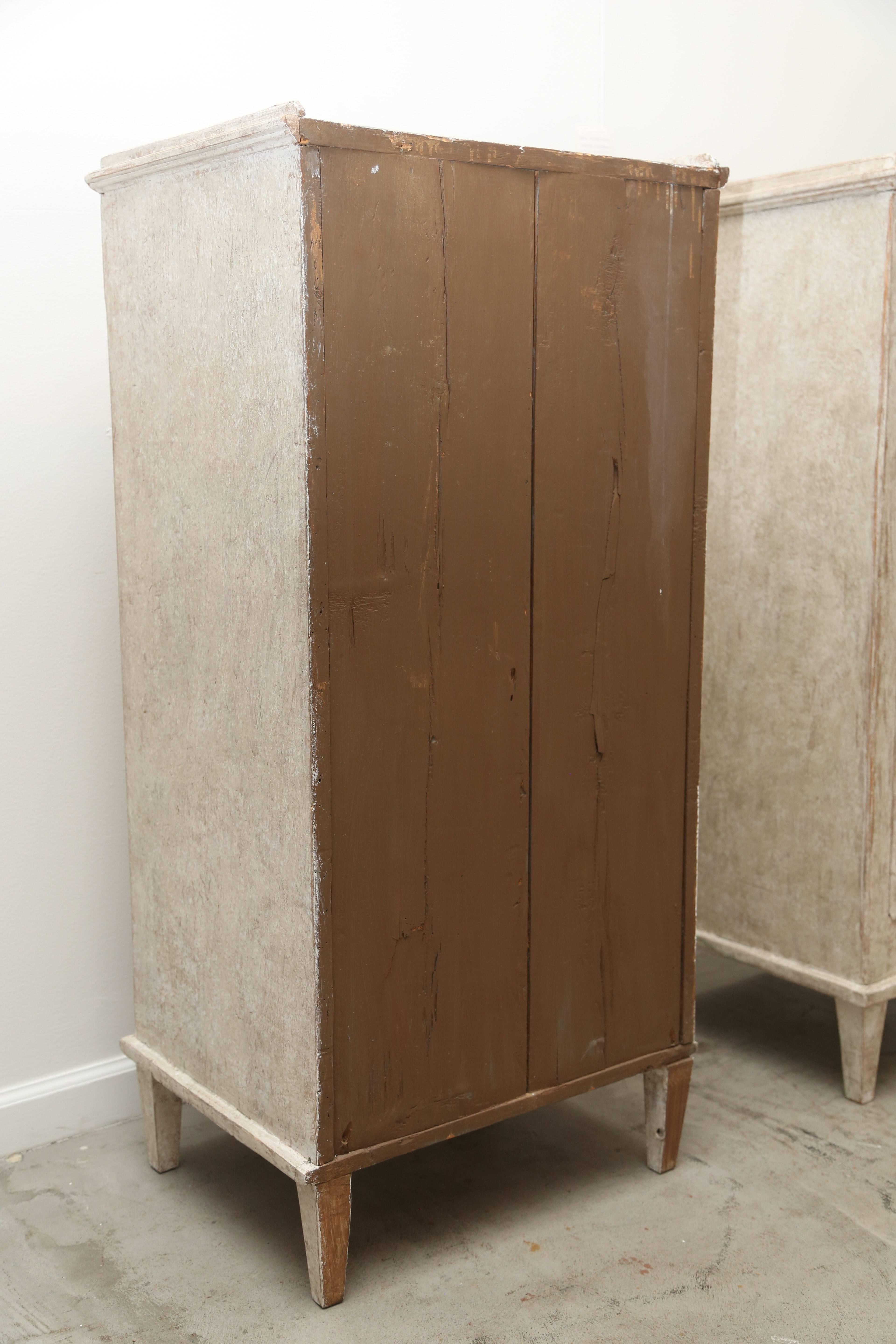 Pair of antique Swedish Gustavian storage cabinets painted in lovely distressed
beige-gray finish. They are taller than usual, nice height to display decorative
items, The doors are recessed panels with arched tops, brass keys plates and keys. The