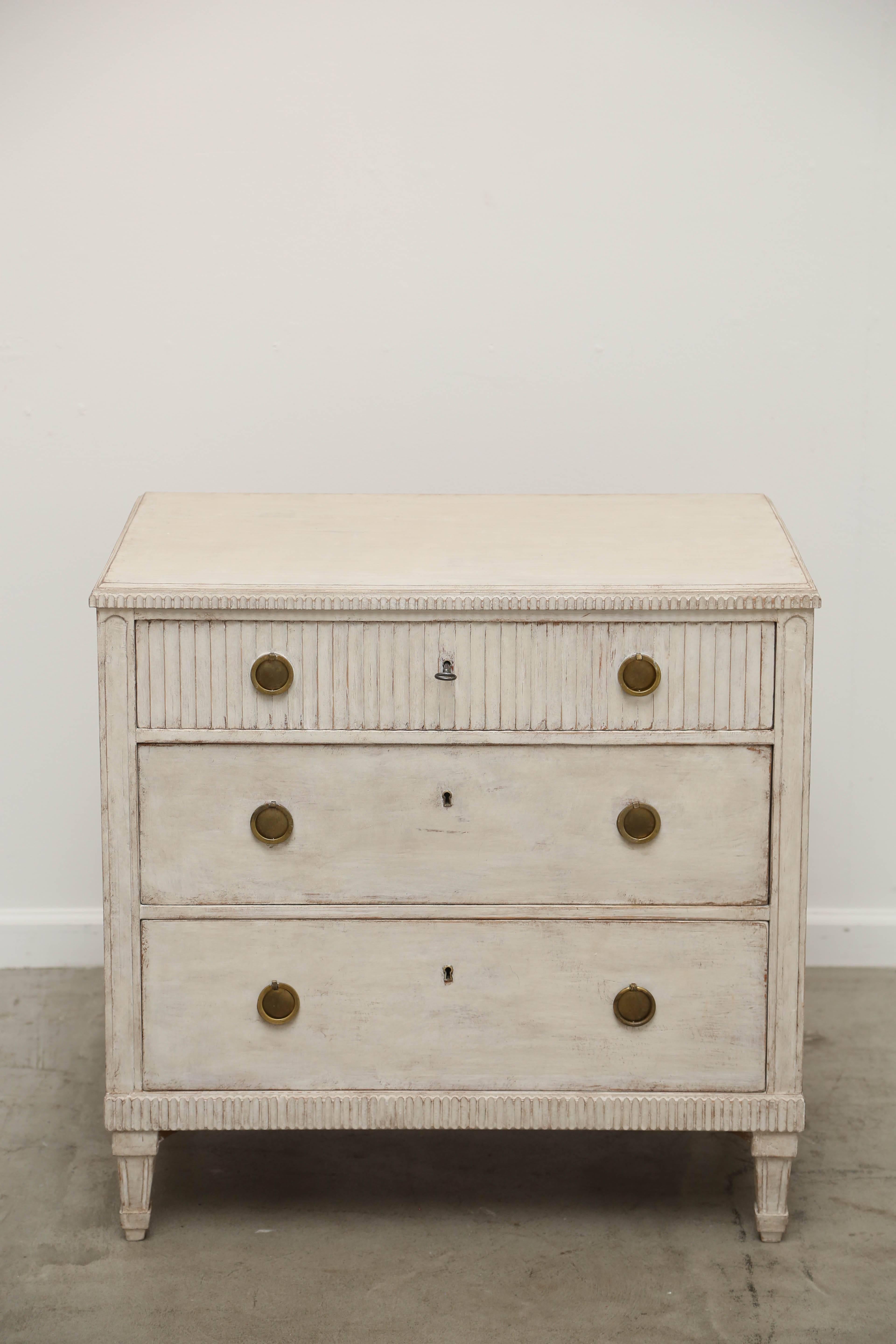 Antique Swedish Gustavian style chest painted Swedish distressed white/ Ivory
finish. Small carved fluted edge around the top, The top drawer has a reeded
carved face, two lower drawer have smooth face, there are brass key holes and
Key. Small