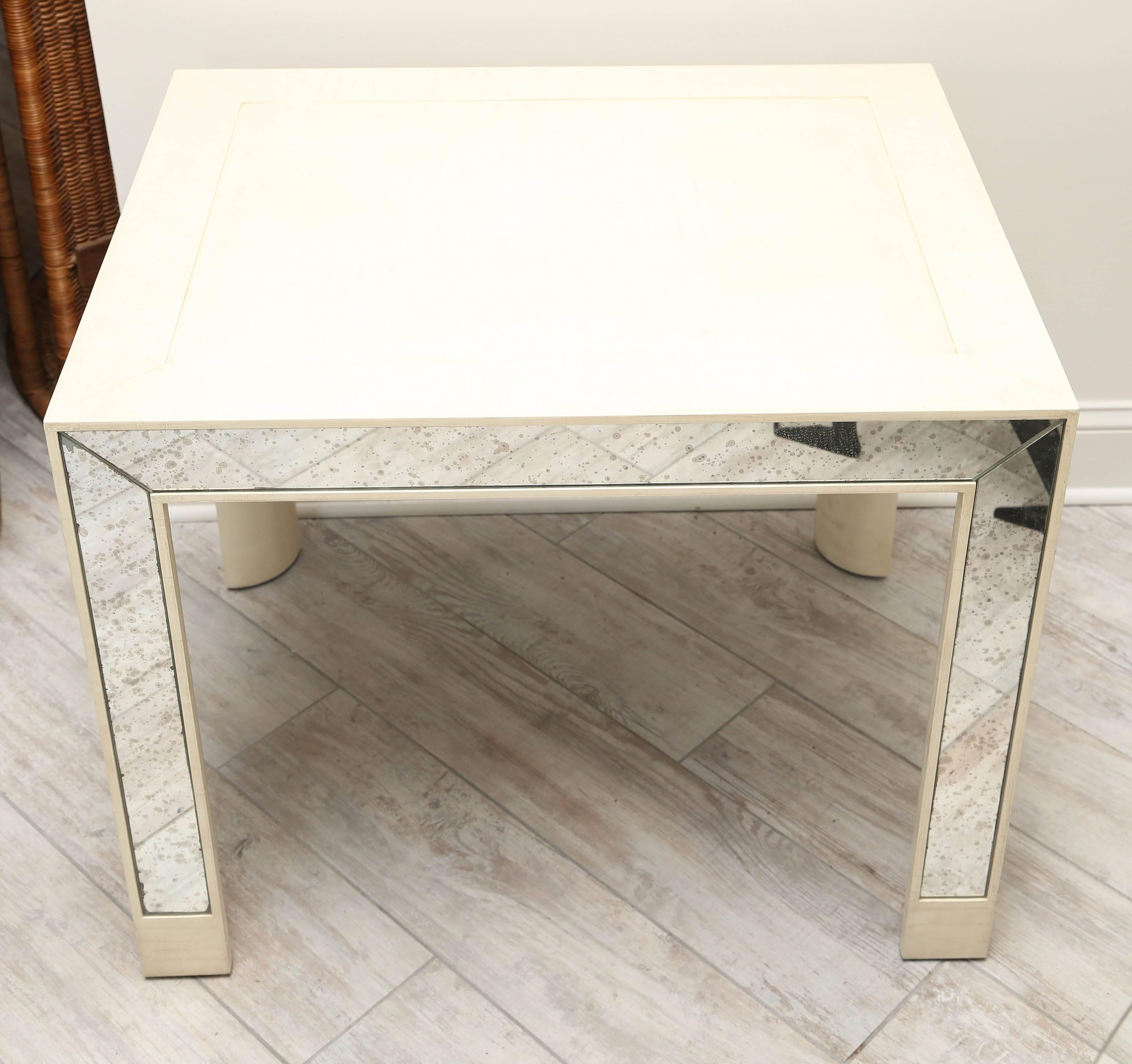 Pair of cream colored parchment finish side tables with mirrored sides and legs.