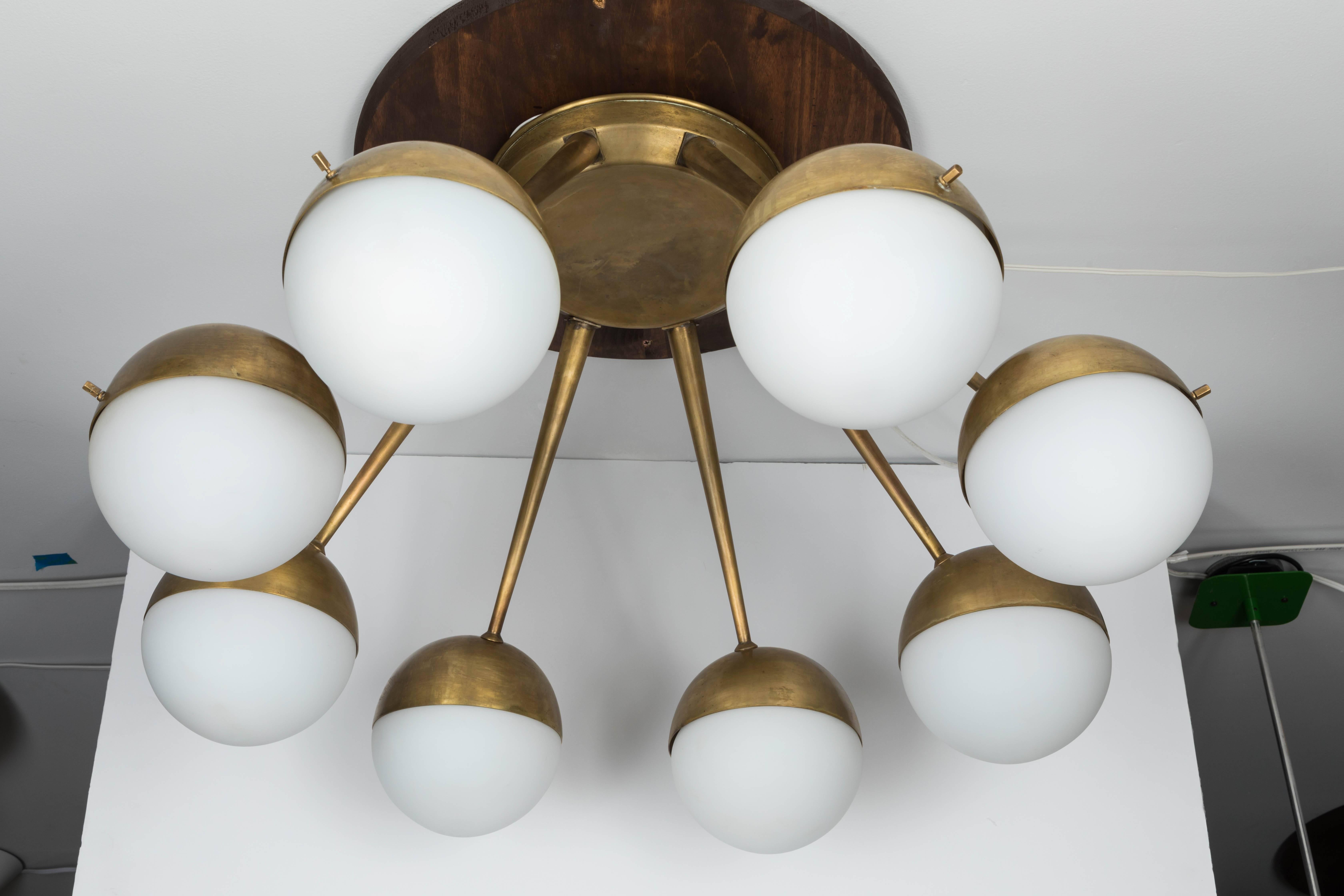 Large 1960s Italian eight-arm brass and glass chandelier Attributed to Stilnovo. Executed in patinated brass and thick 6 inch diameter matte opaline glass globes. A sculptural and refined design characteristic of 1950s Italian design at its highest