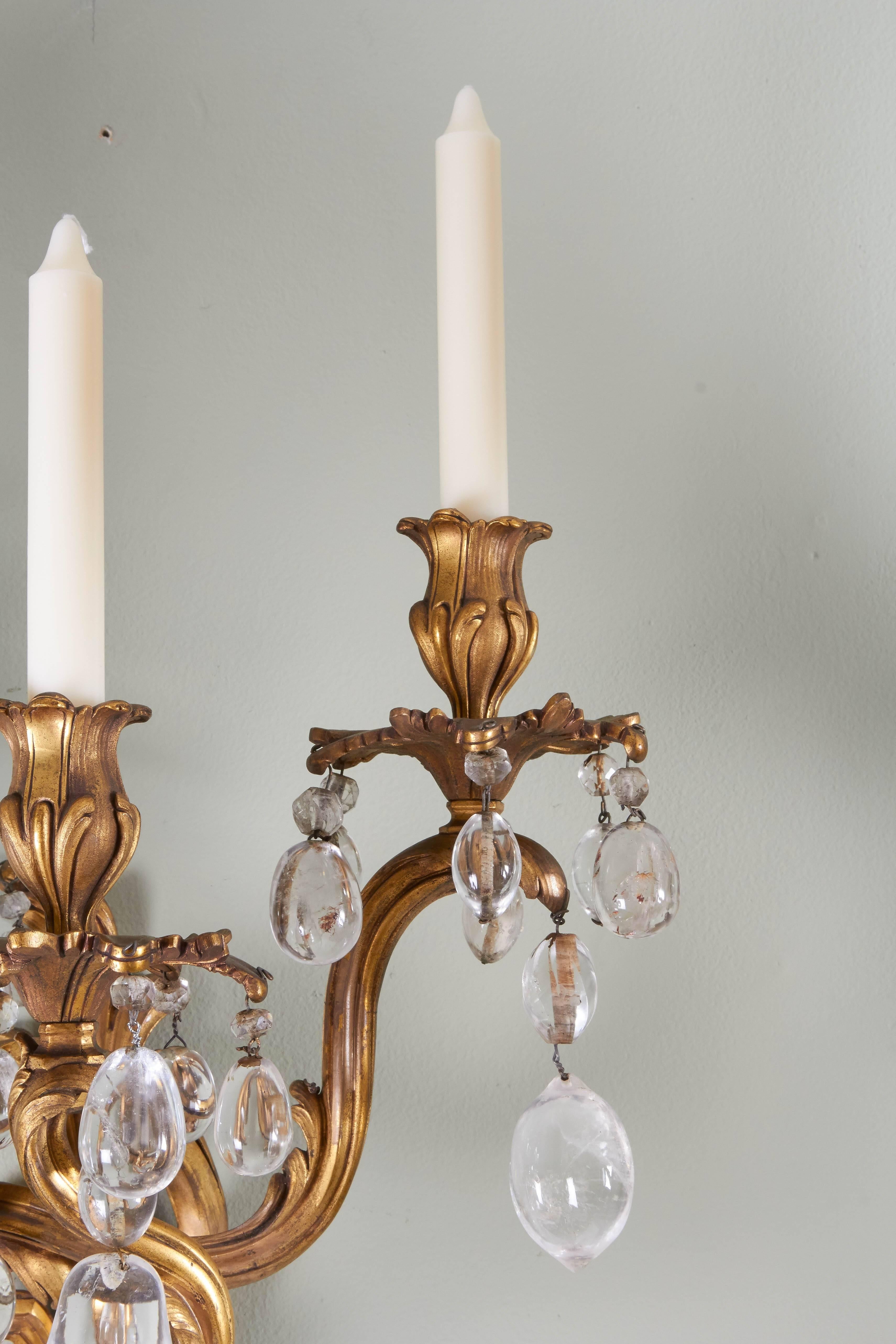 A pair of Louis XV style bronze dore and rock crystal sconces, foliate form draped overall with rock crystal prisms, wired for electricity 