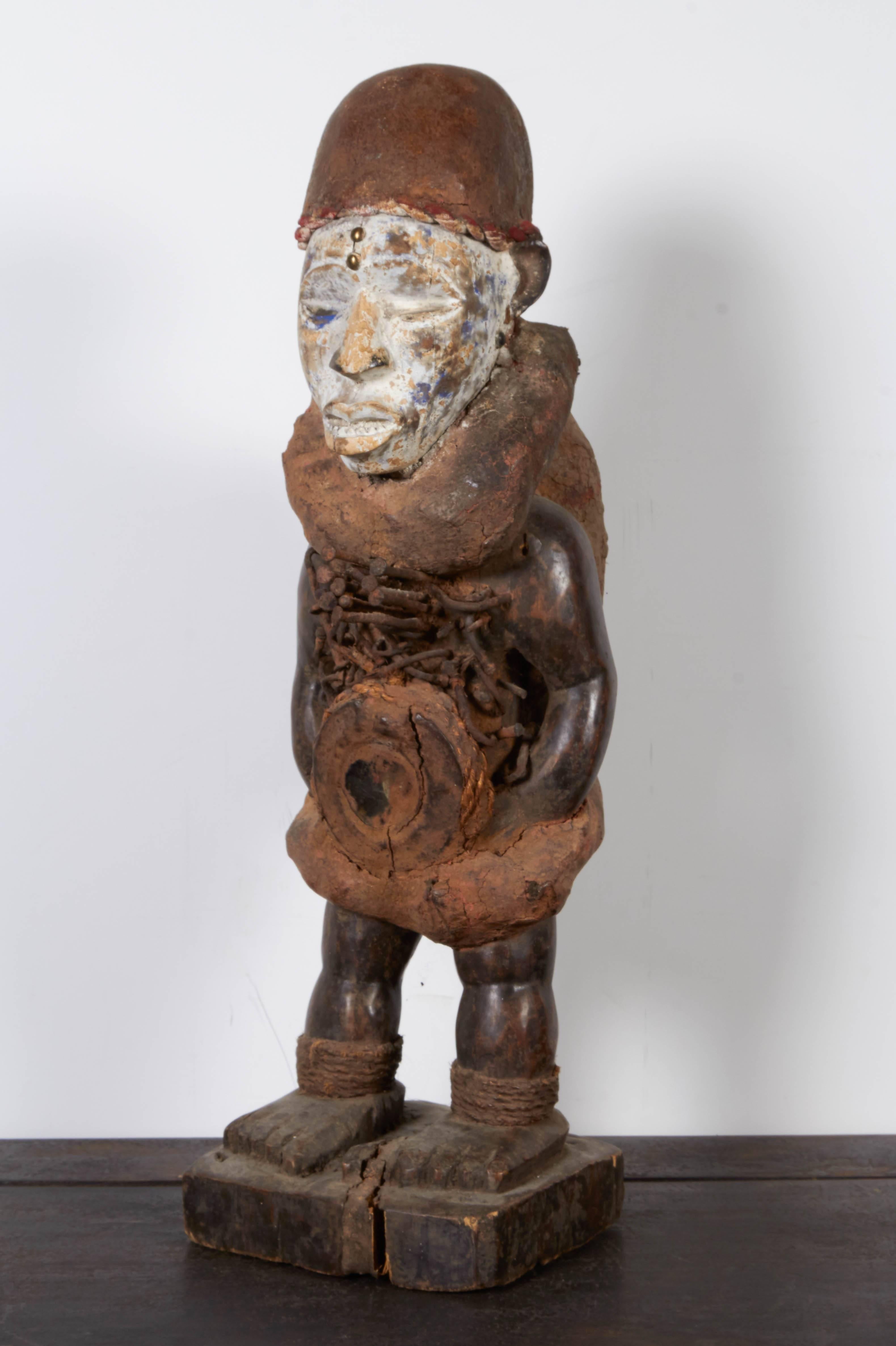 A worn, weathered and finely carved and colored divination figure from the Congo. This very detailed African carving features a striking face with faded white paint emphasizing his expression. Diviners are often consulted regarding solving important