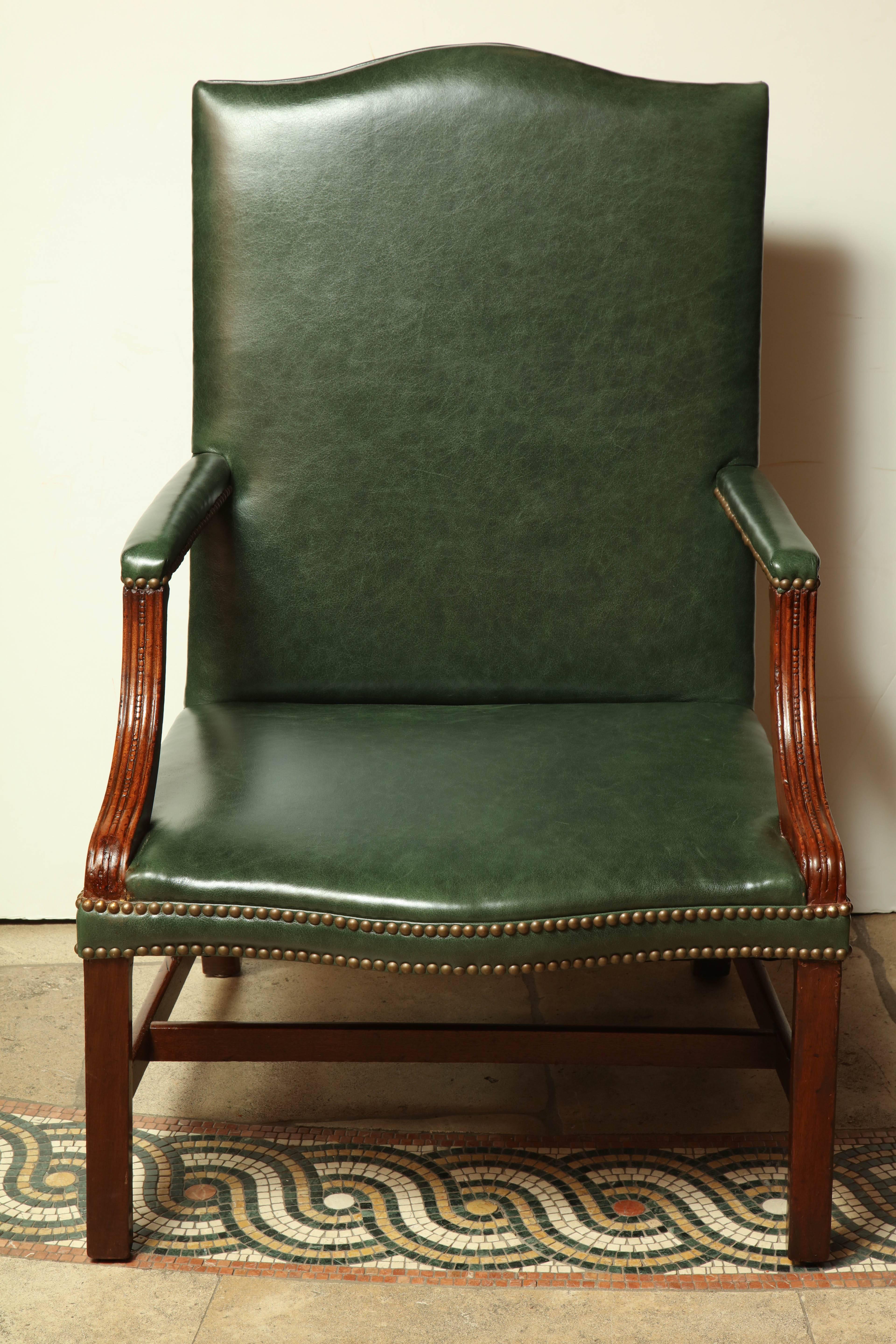 A George III carved mahogany leather upholstered Gainsborough armchair with H stretcher base.