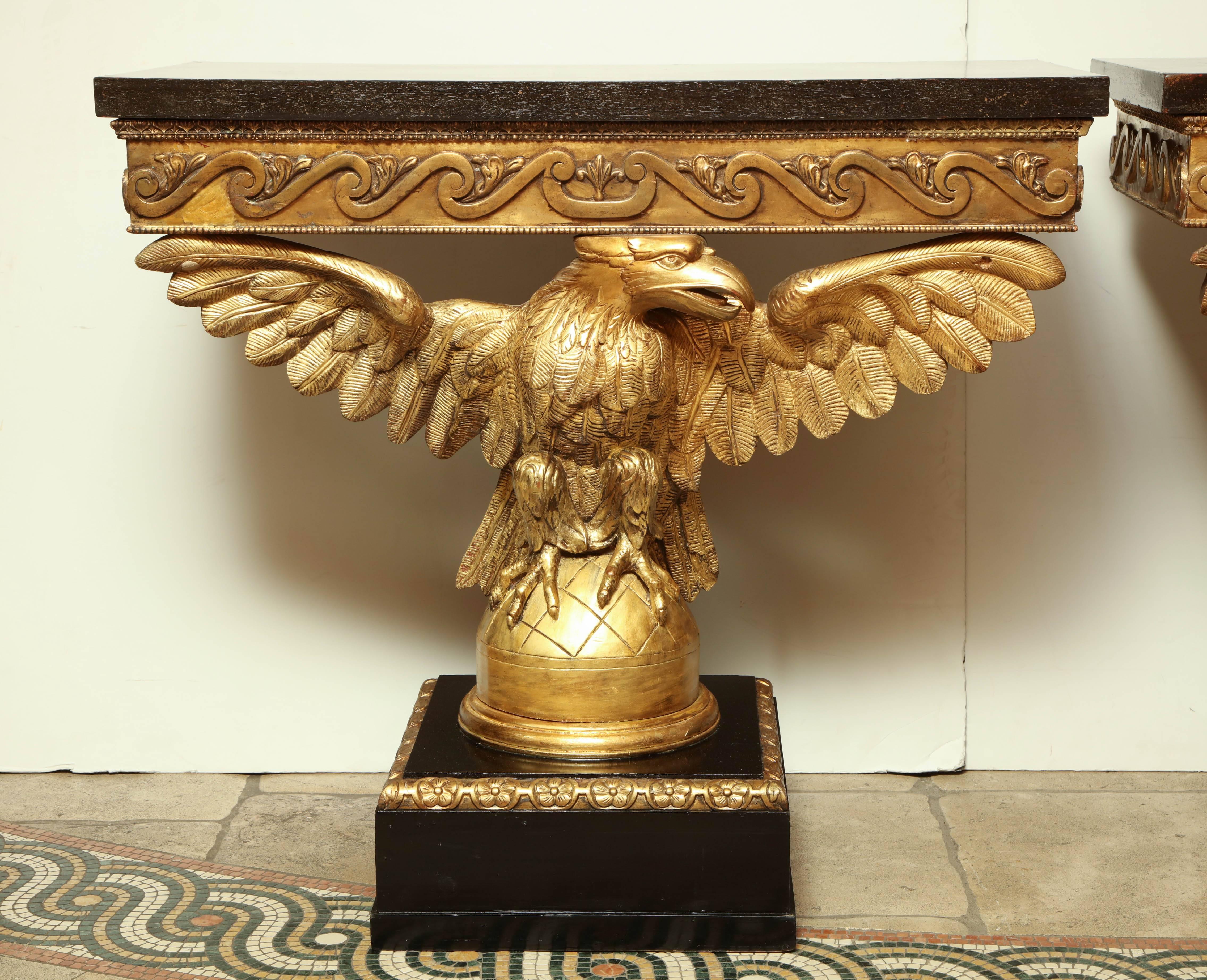Pair of George I style carved and gilded eagle consoles with painted faux marble top, carved Vetruvian scrolls on a square plinth base.