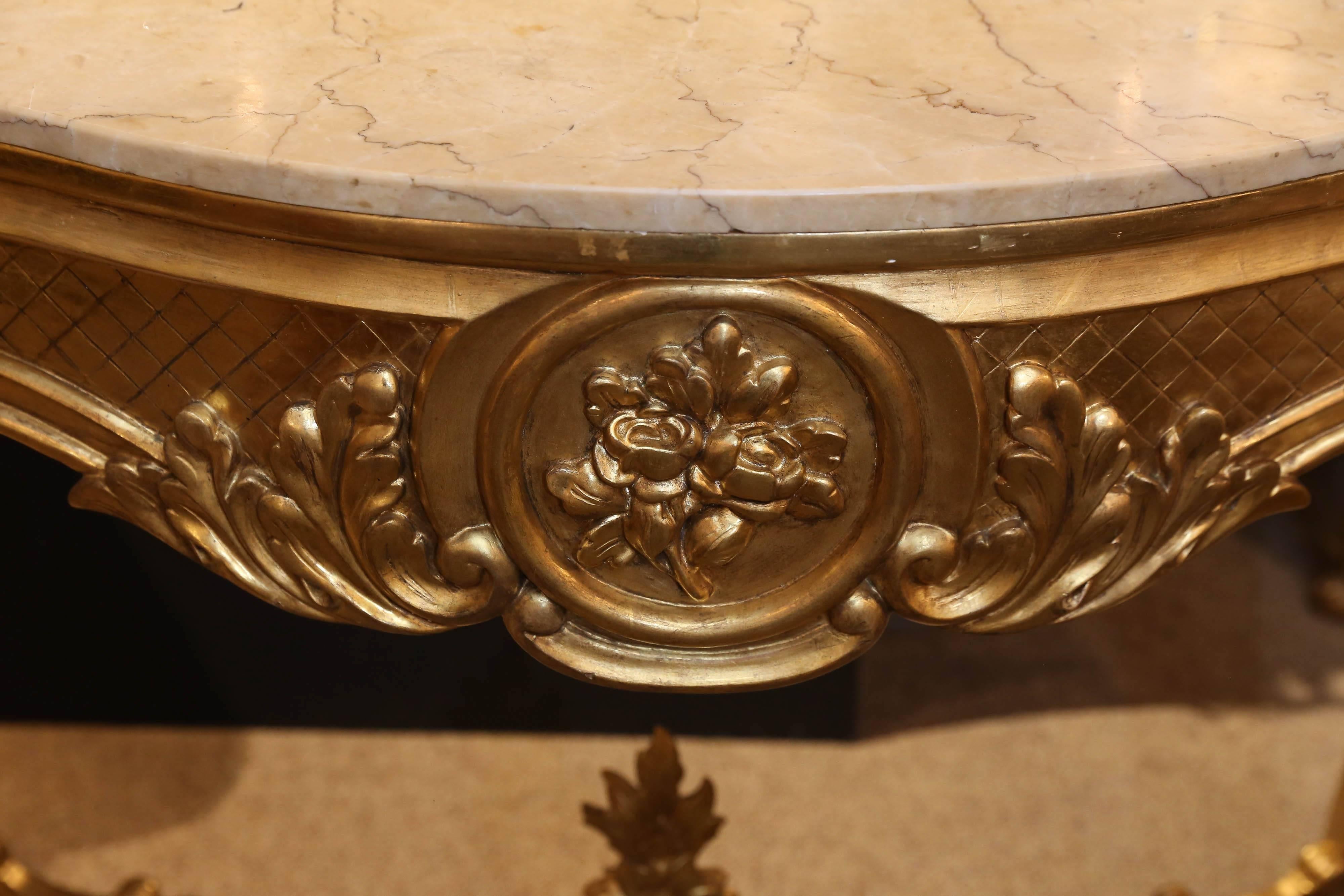 giltwood French Louis XV style console, with cream marble top
An X-form stretcher connects the legs at the bottom of this 
Piece and a floral carved finial decorates the center
Floral motif is carved within carved circular forms on the
Center